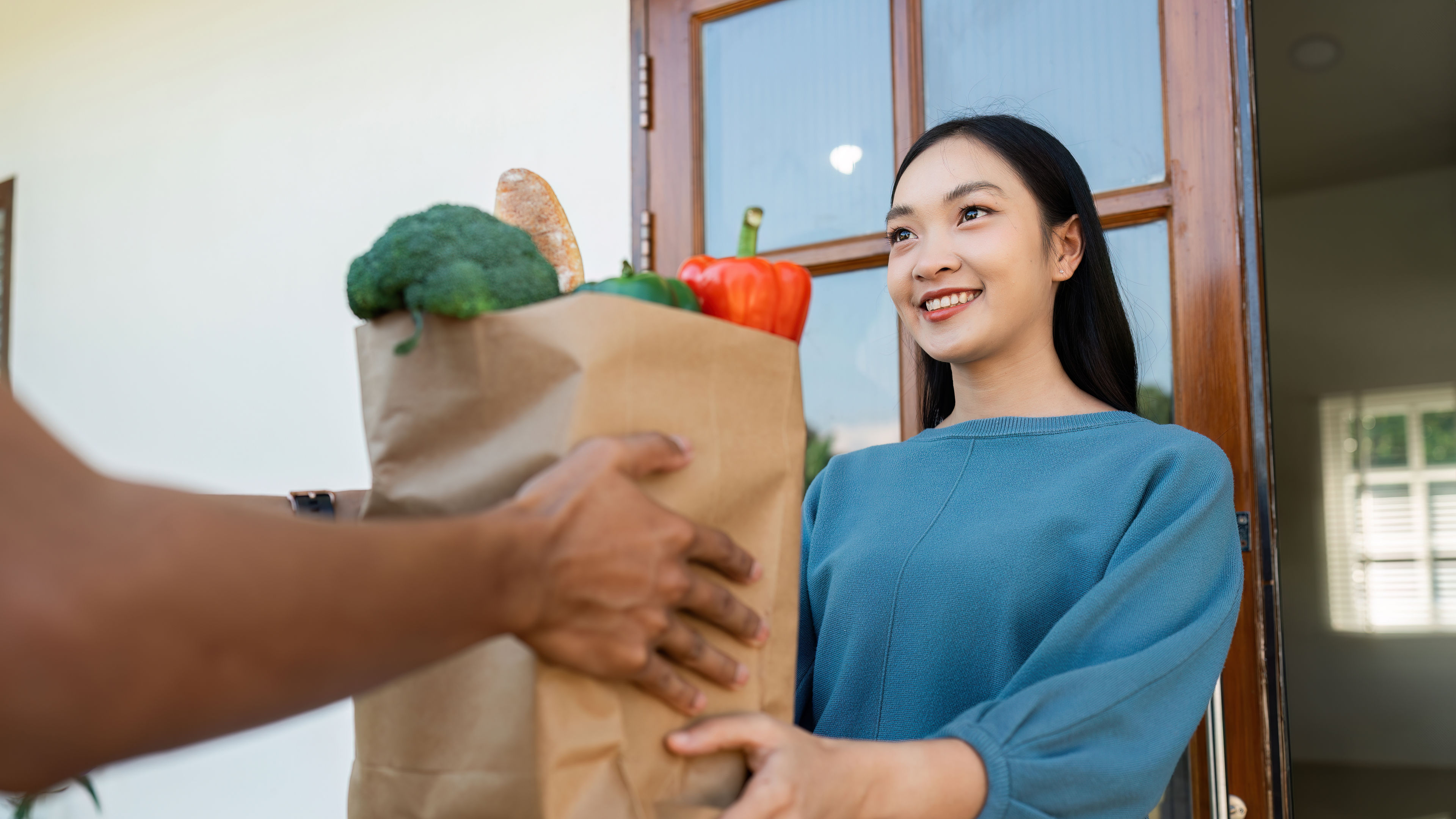 Isang babae na kumukuha ng meal kit mula sa isang delivery man