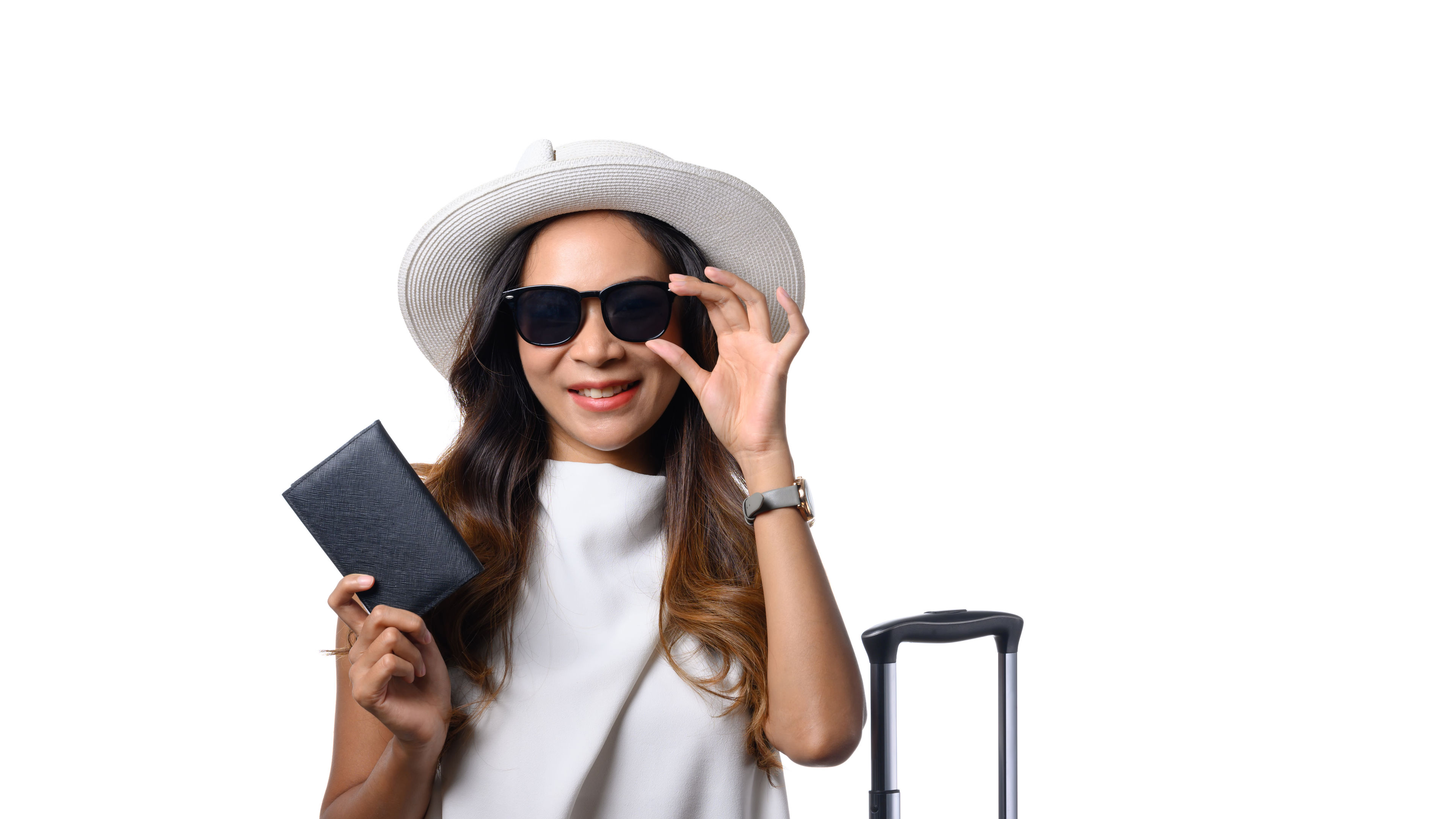 Nakangiting babaeng biyahero na may hawak na pasaporte nakatayo na may maleta sa puting background 
