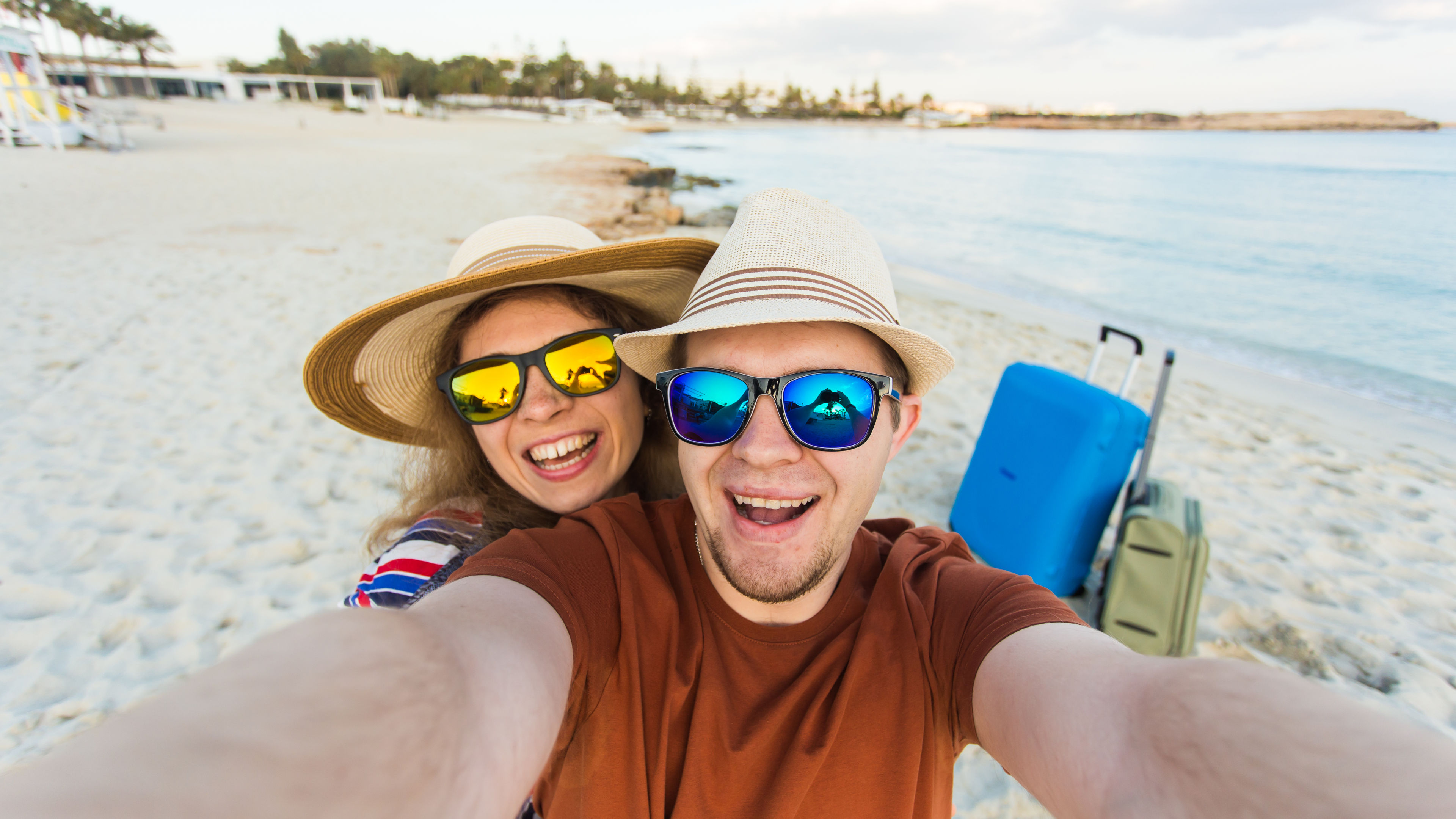 Happy traveling couple in love taking a selfie on phone at the beach on a sunny summer day.