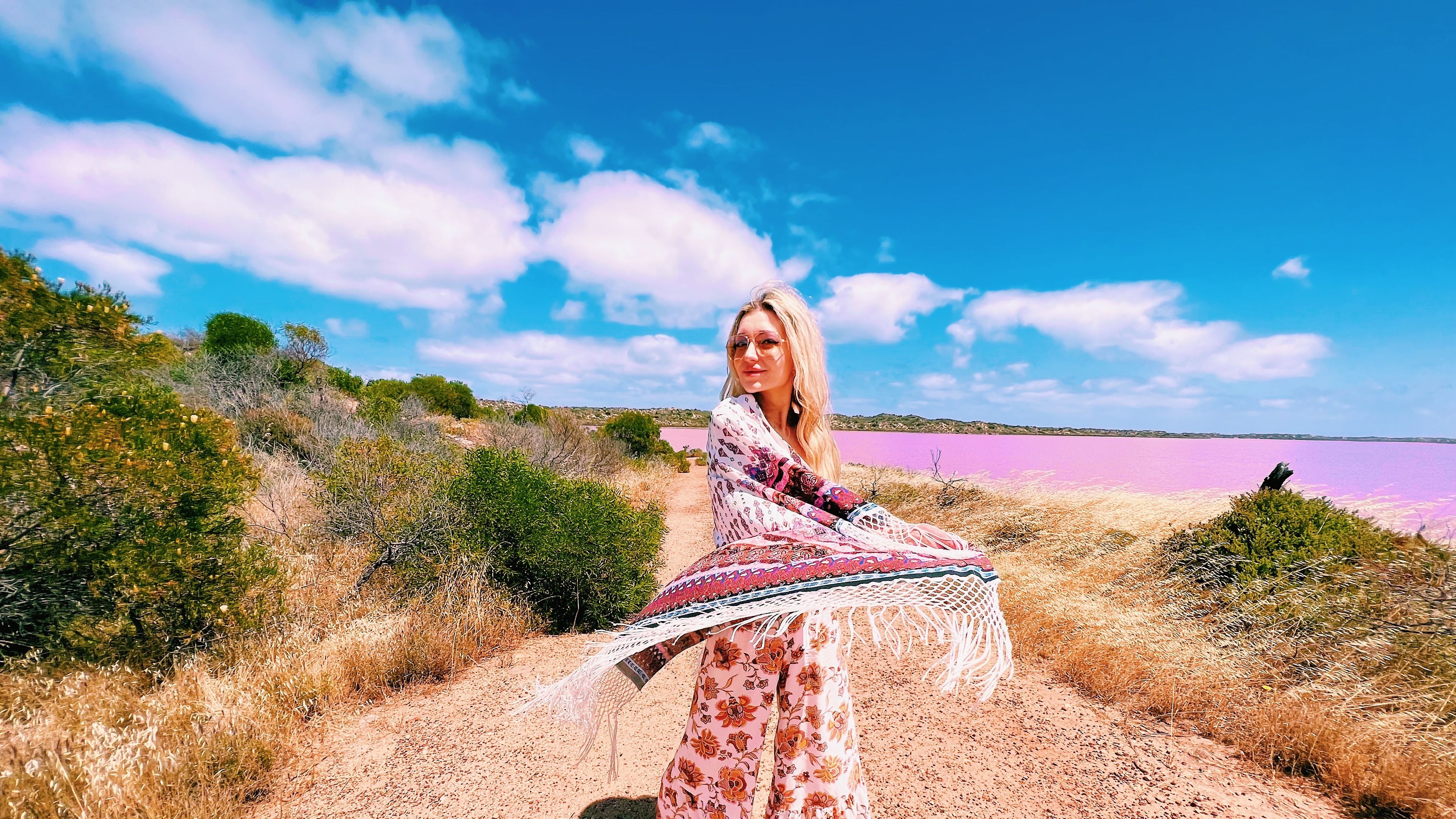 Beautiful young traveler girl wearing boho outfit exploring pink lake in Australia 