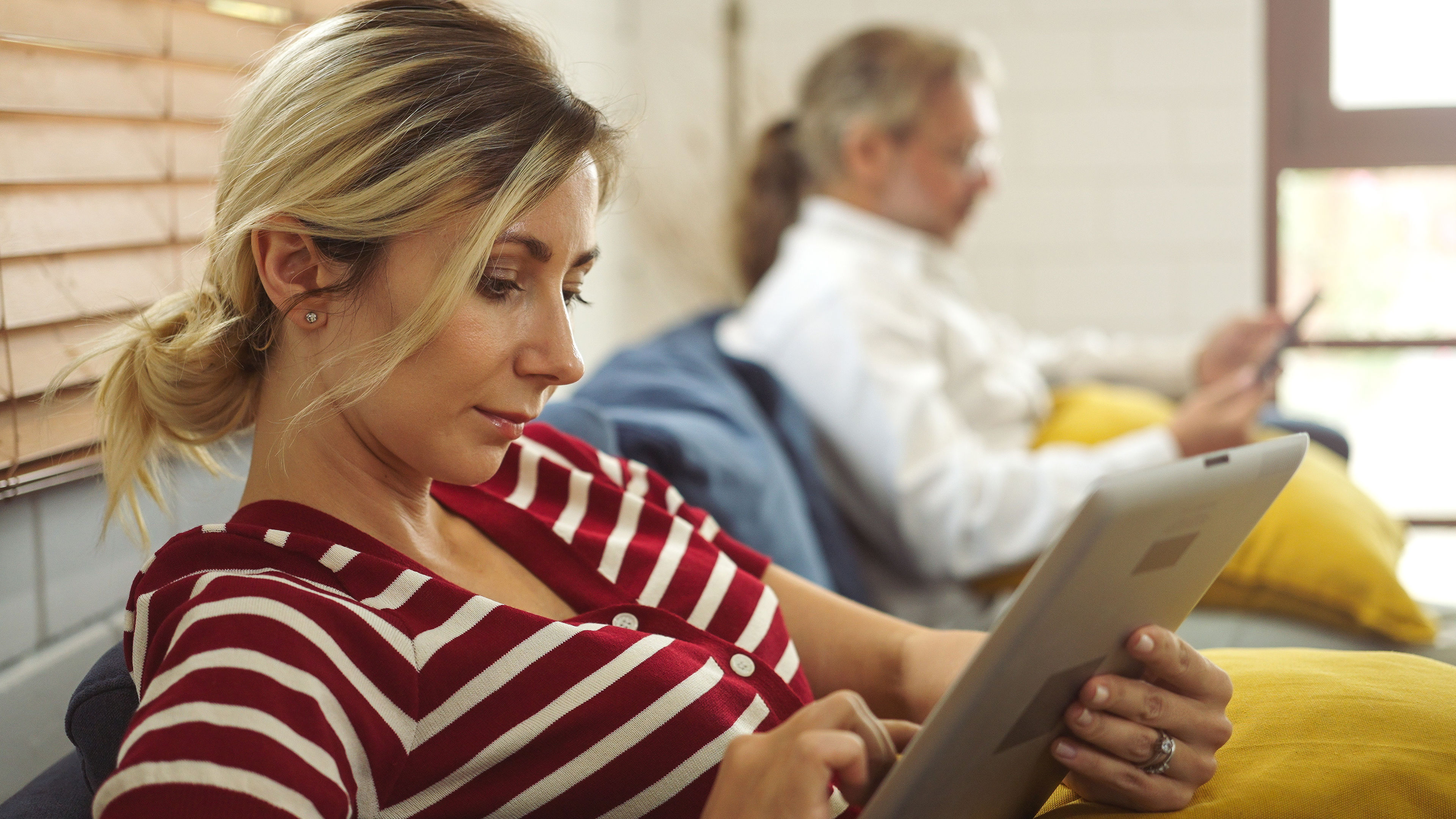 father and dauther holding and using different electronic devices while sitting on the sofa