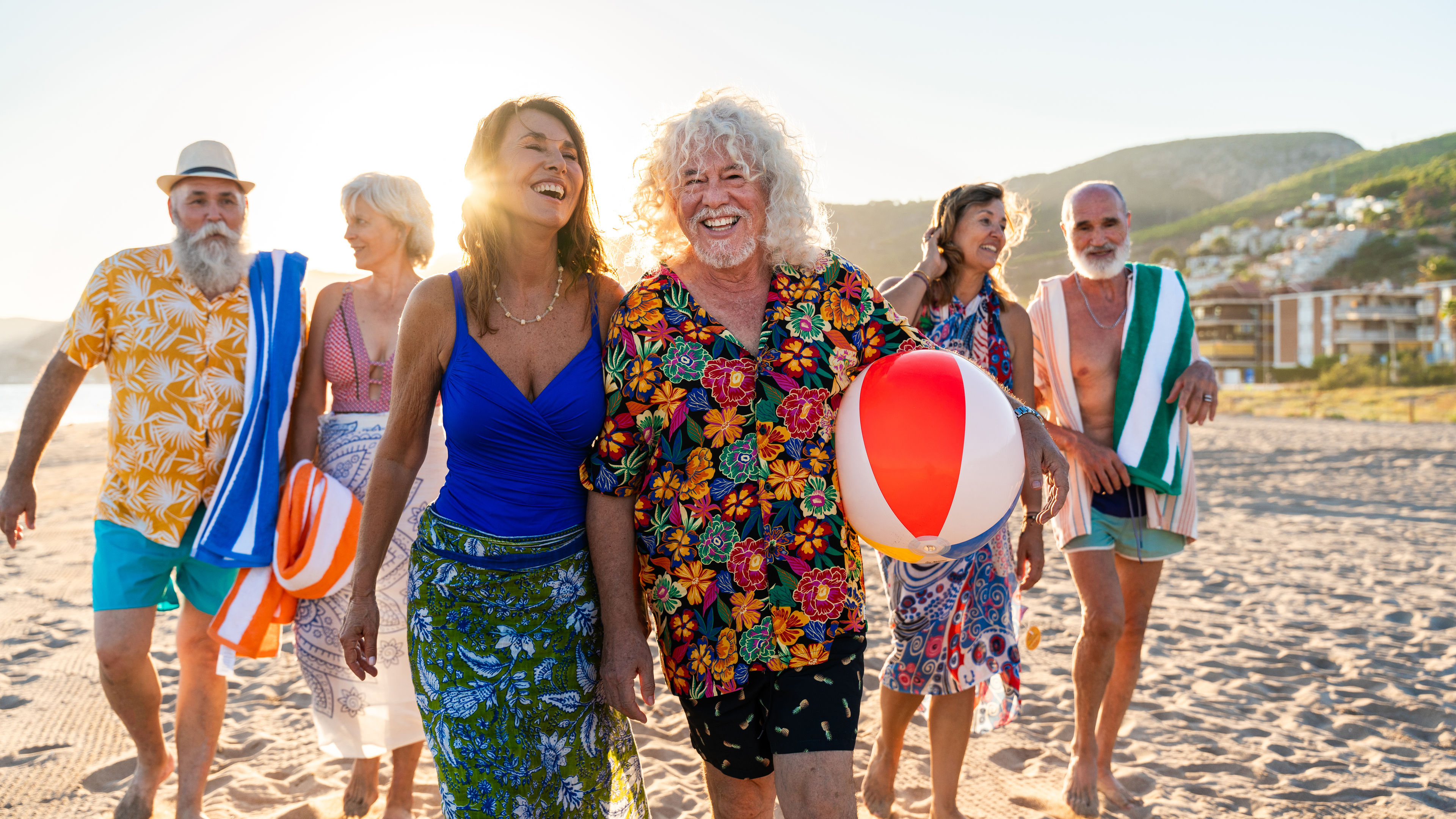 Happy group of senior friends bonding at the beach during summertime 