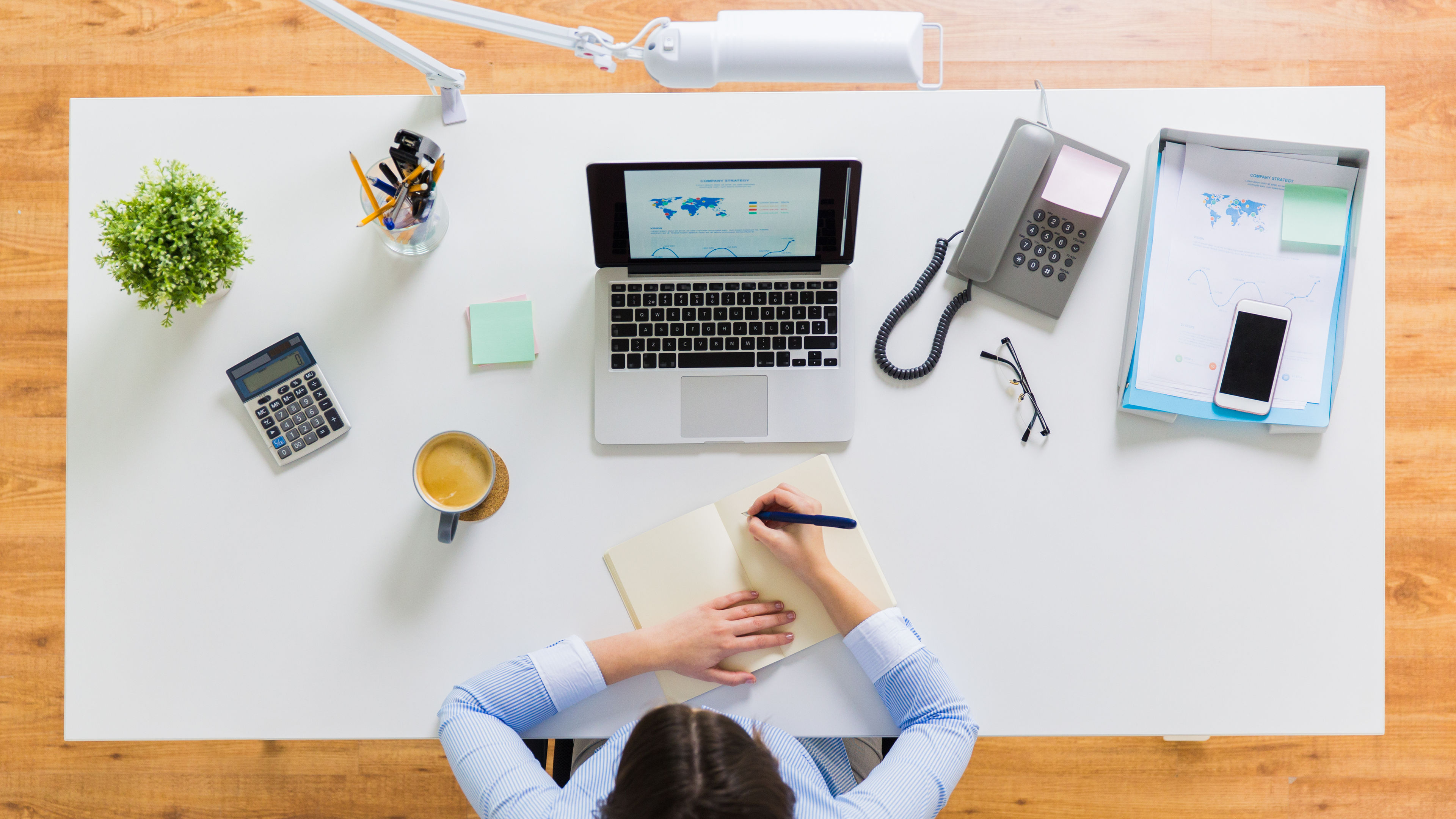 Image of employee writing on a white desk