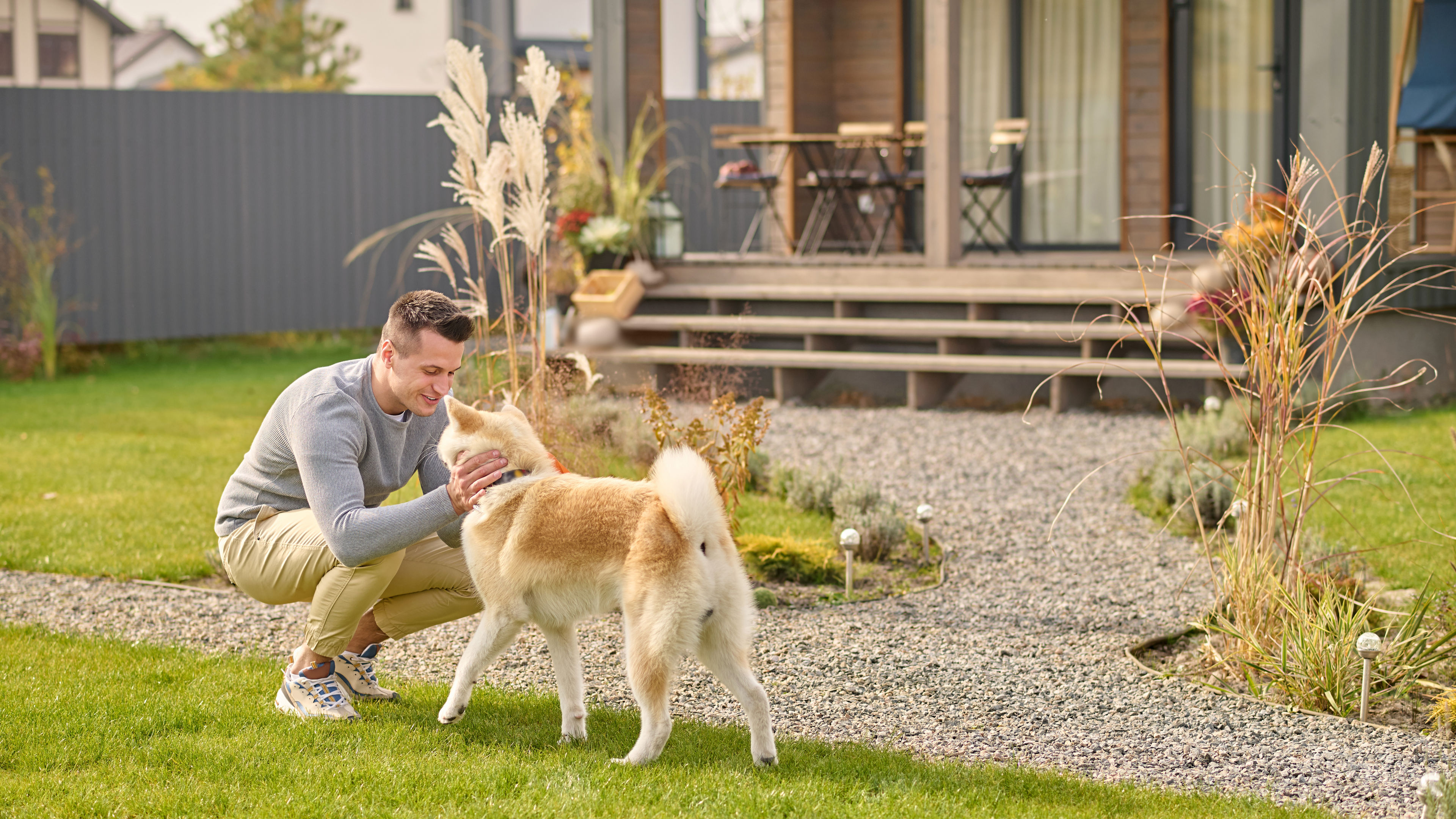 Man crouching and looking at his dog outdoors. 
