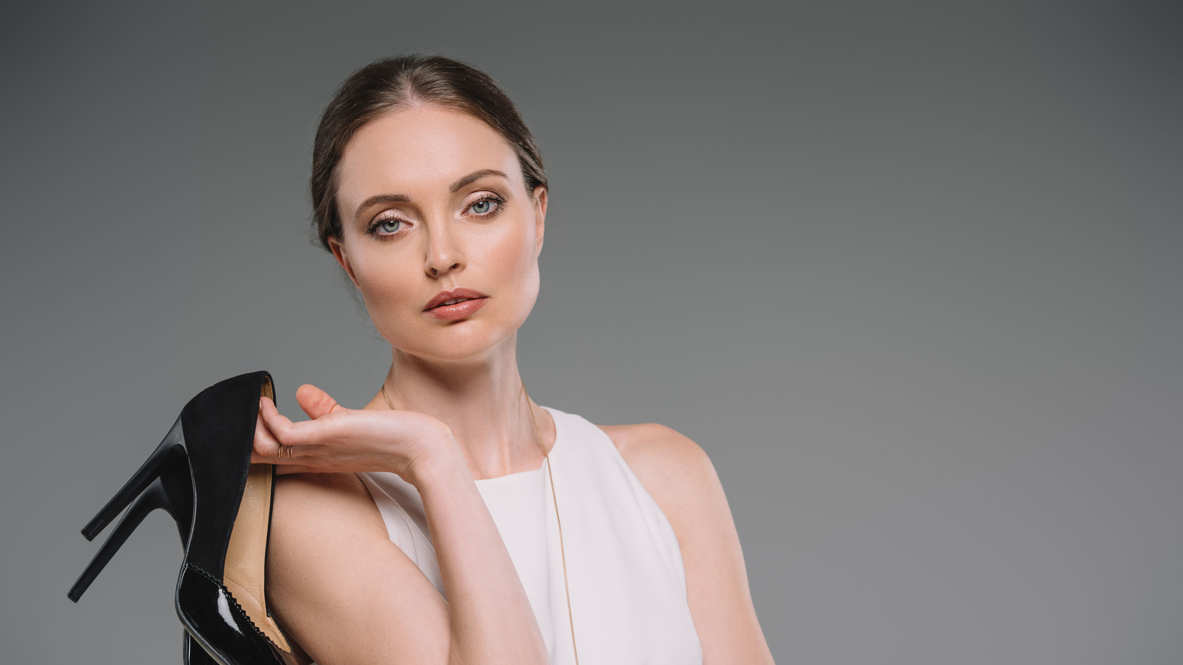 portrait of attractive businesswoman looking at camera and holding shoes with high heels.