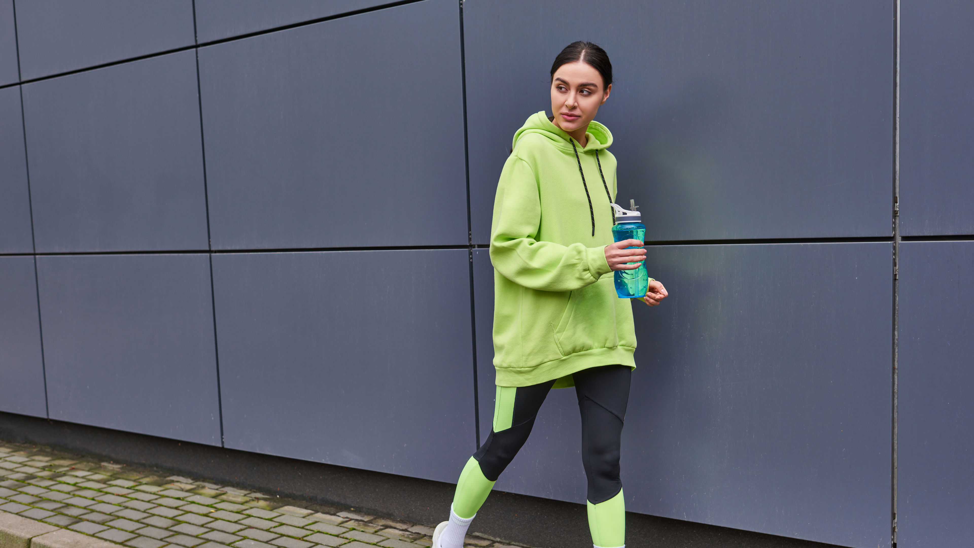 Beautiful sportswoman in a hoodie and leggings walking. 
