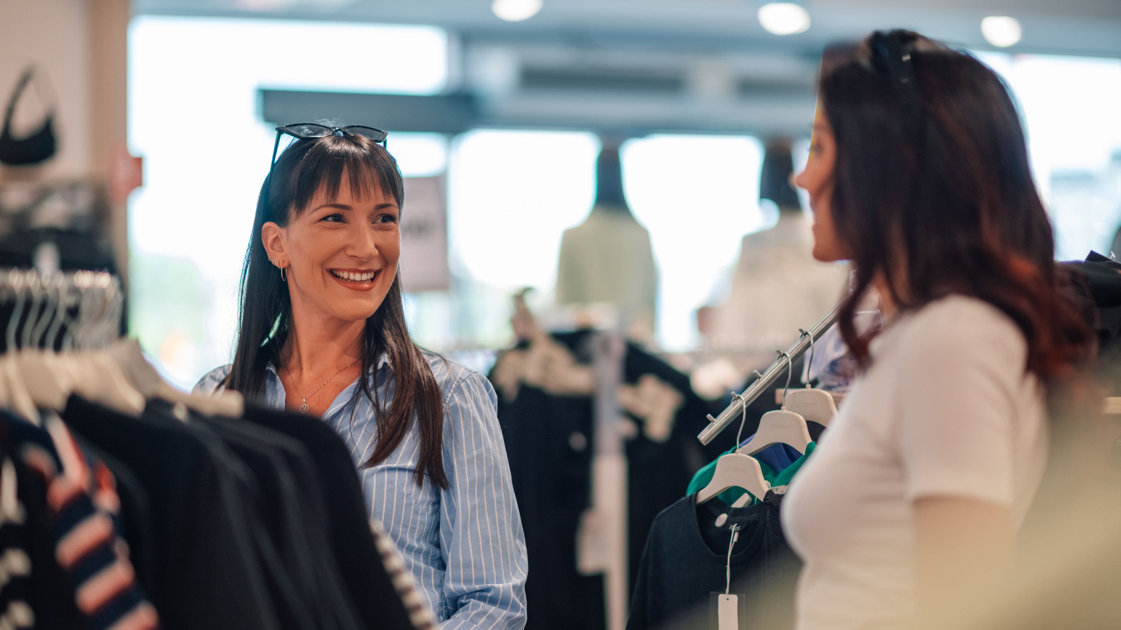  Two smiling women shopping at a clothing store. 