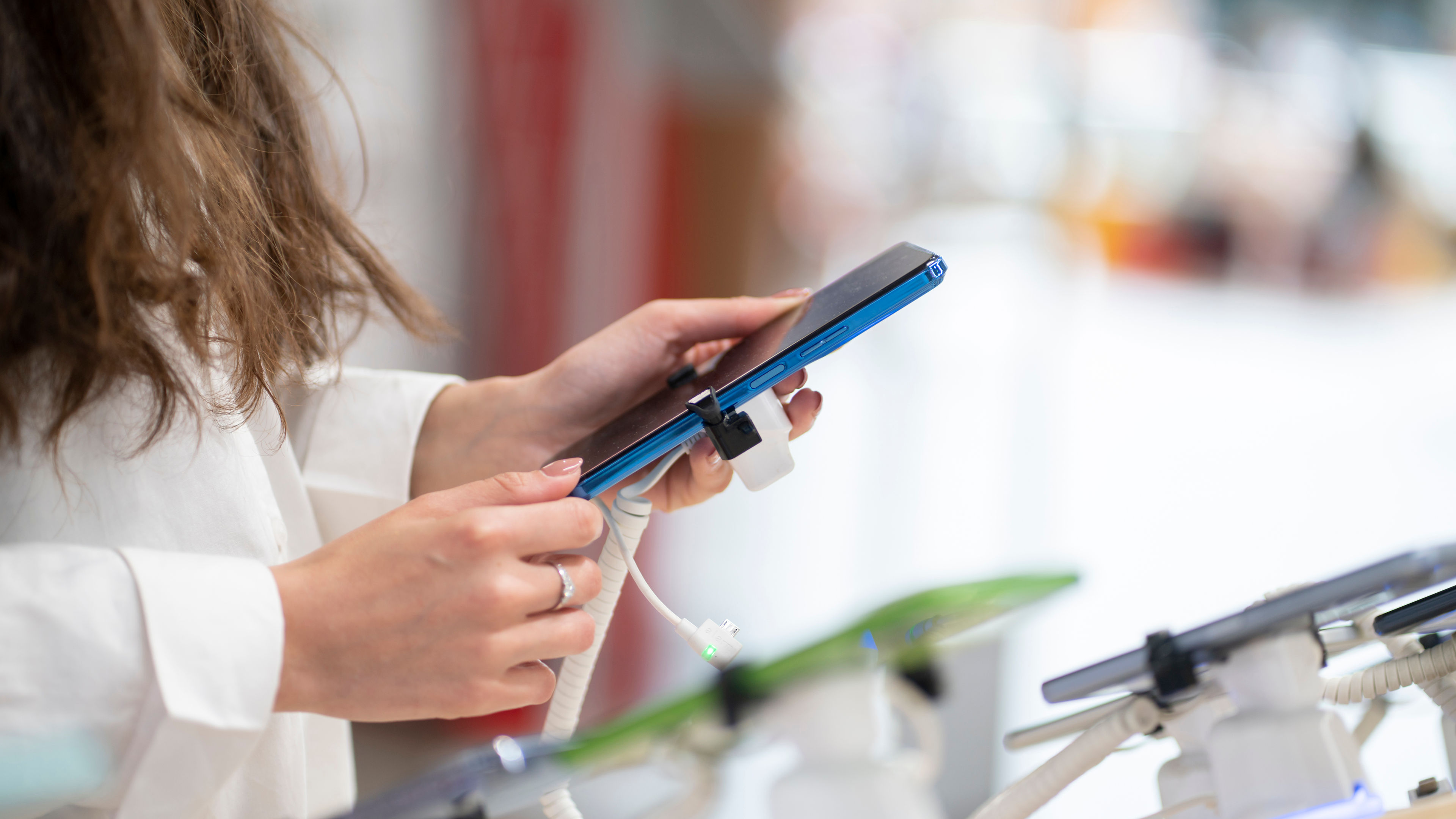 A woman in the electronics store with cable for her phone.