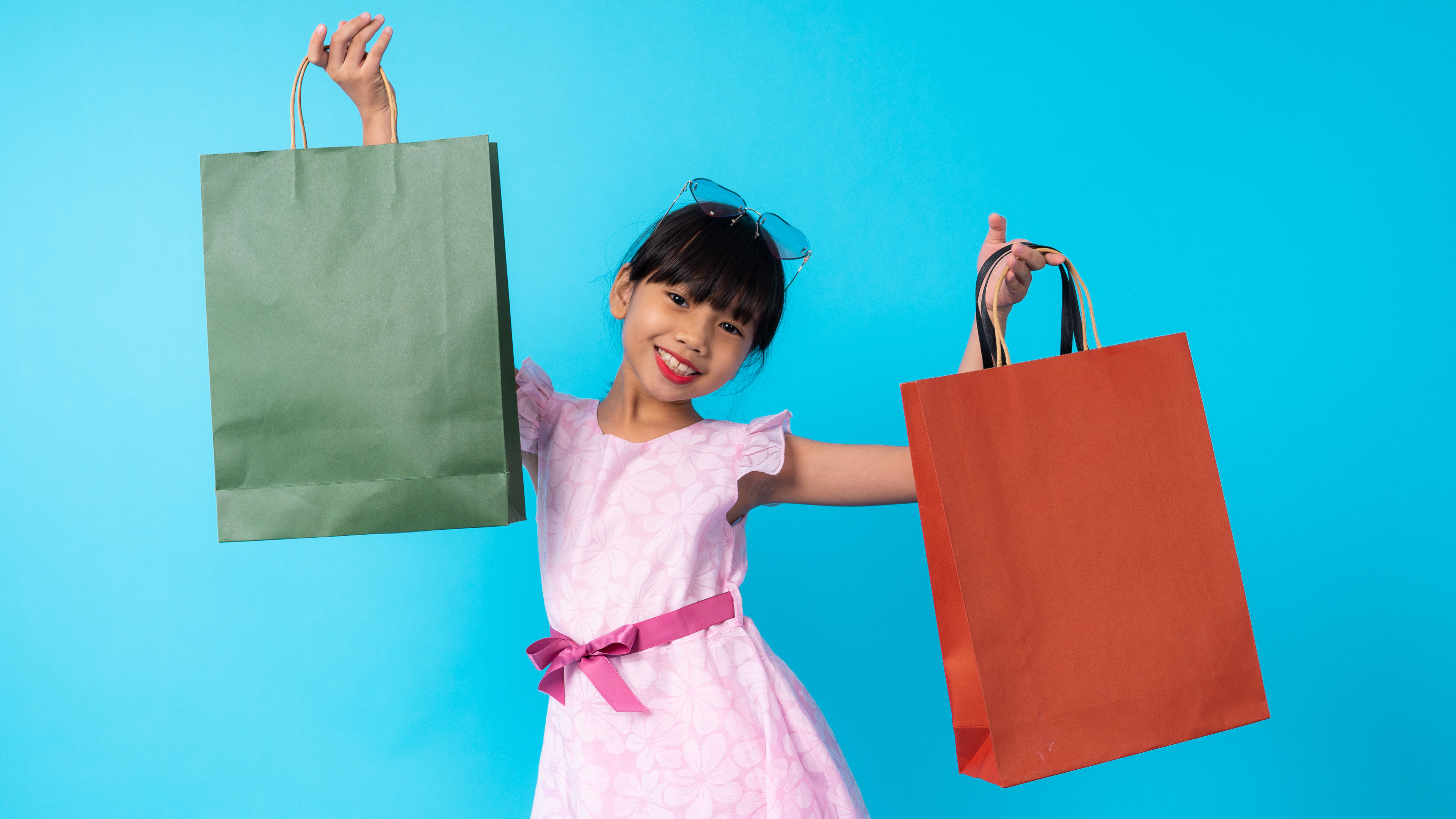 A smiling young girl holding two shopping bags