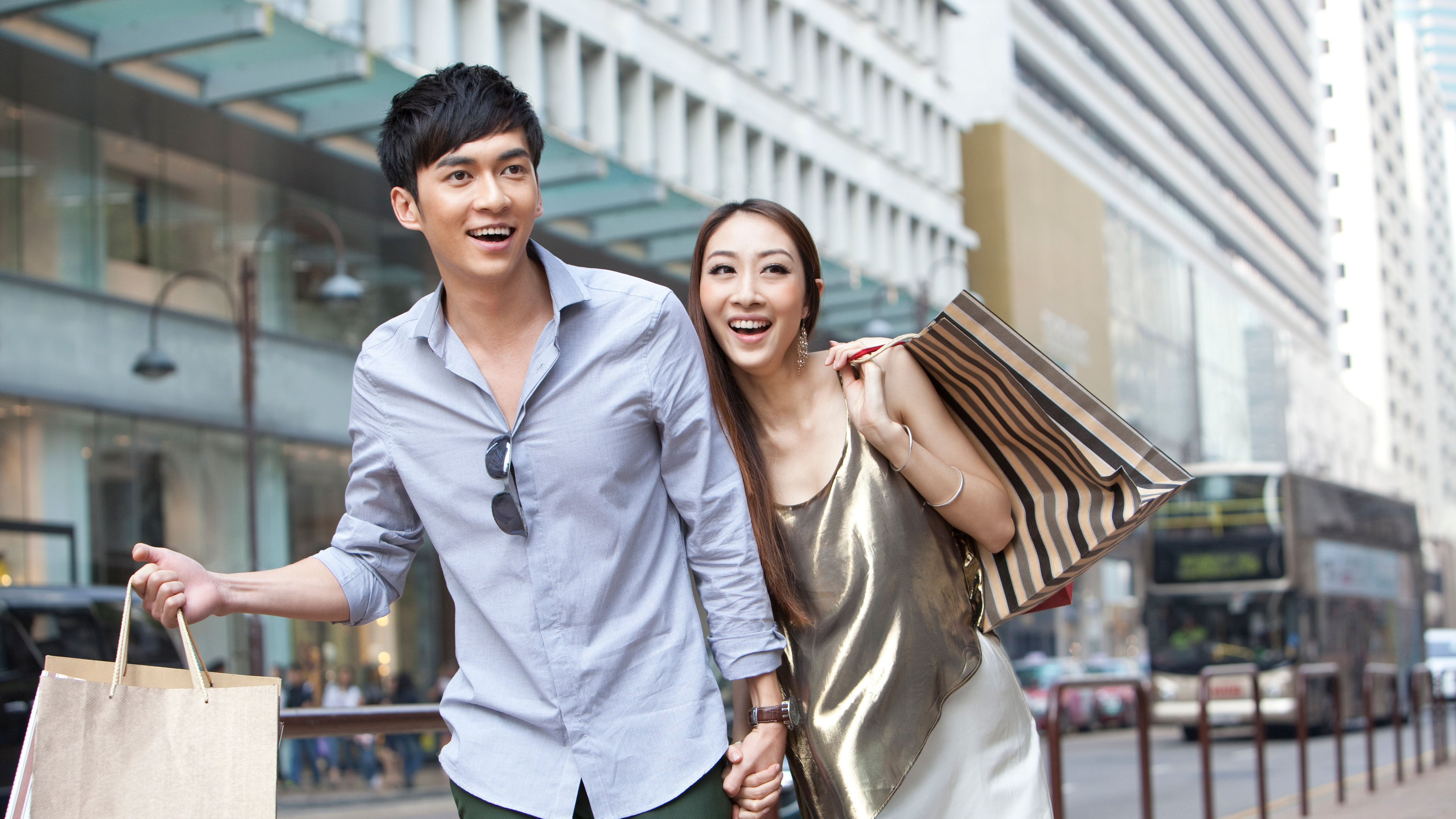 Cheerful young couple with shopping bags walking in the street, Hong Kong 