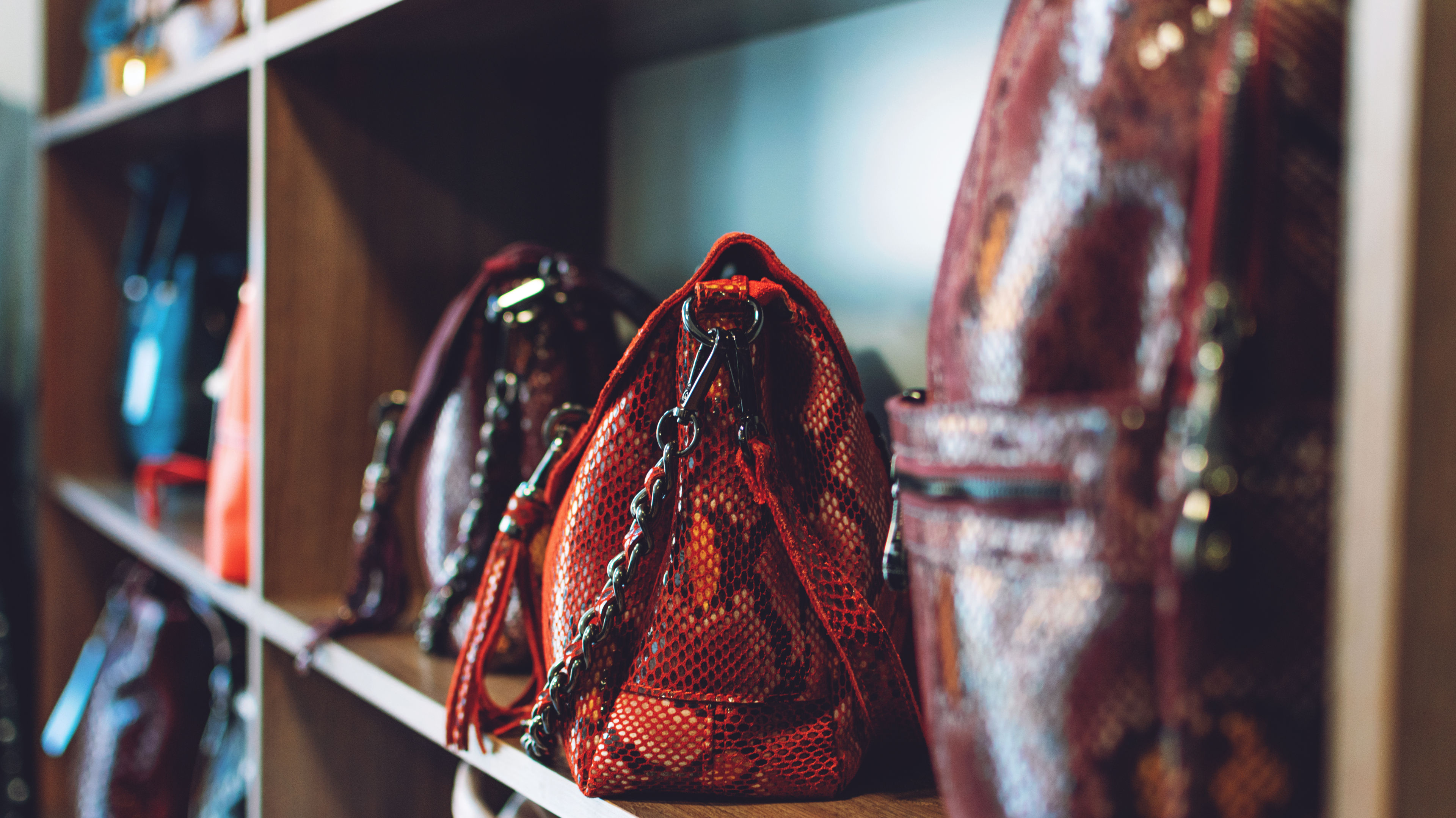 Fashion trend snakeskin print handbags on shelf in a store, shop. Sale, shopping, accessories