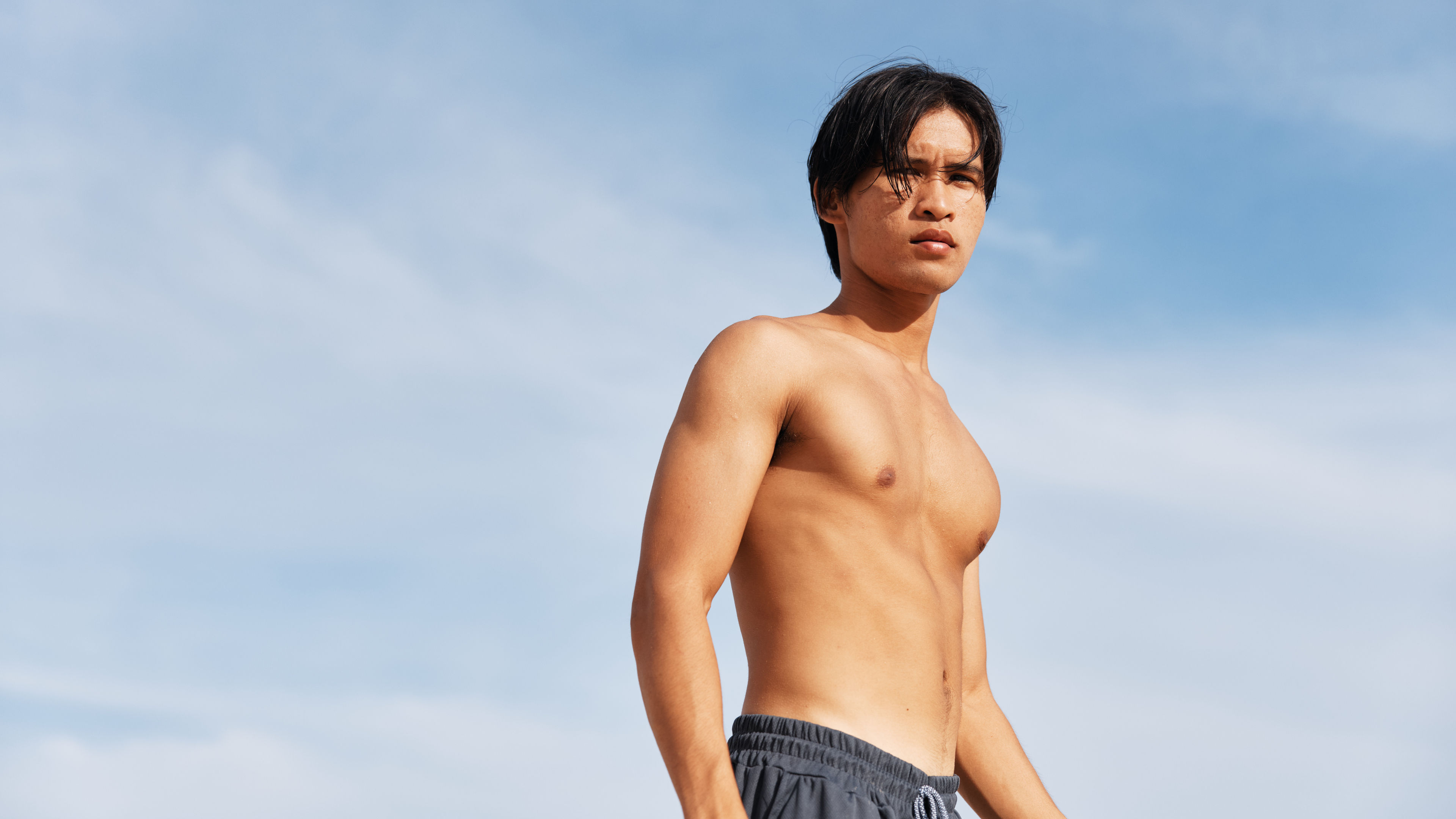 Happy Asian Man Enjoying Beach Vacation Muscular Torso and Smiling in Tropical Paradise