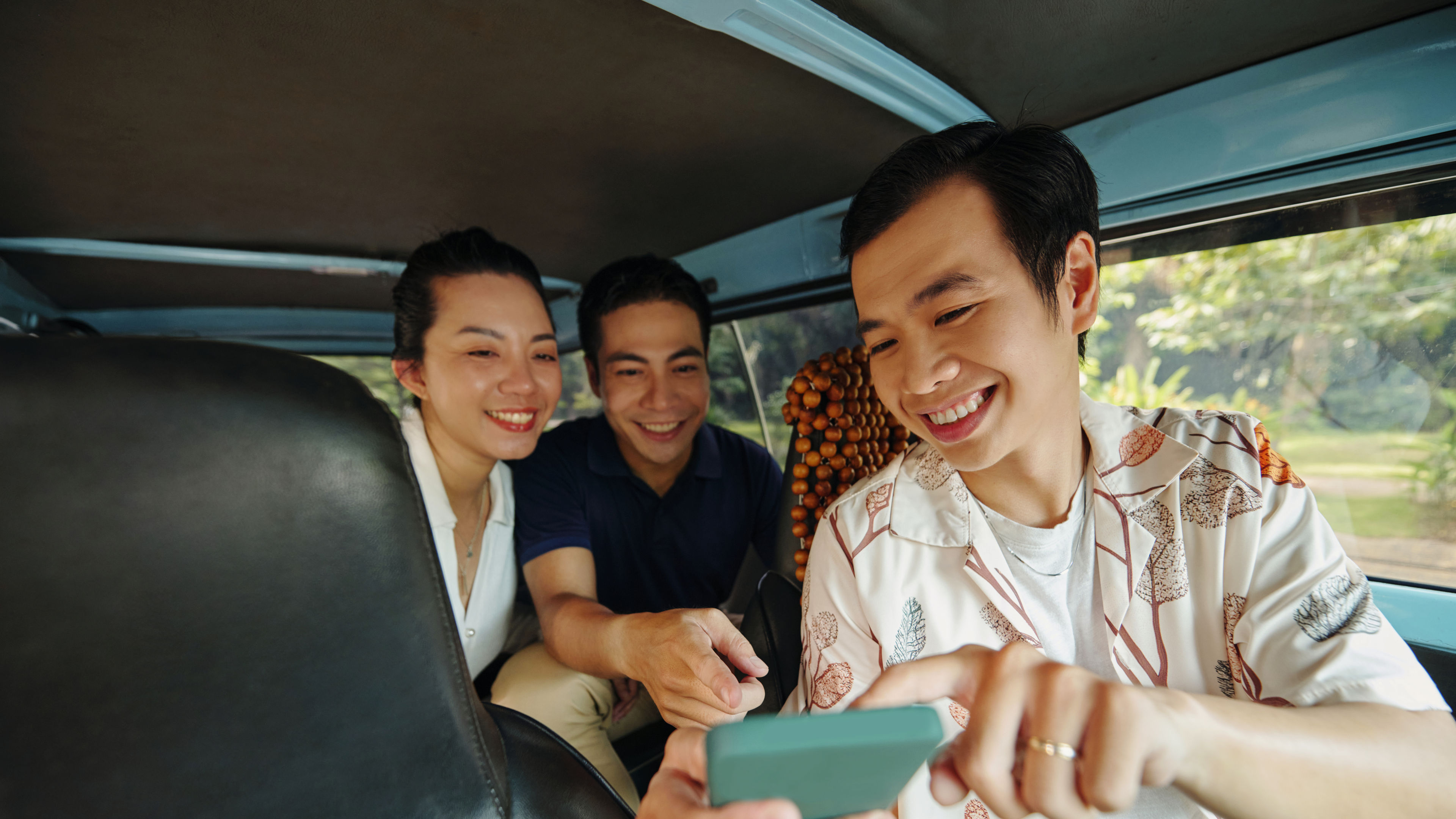 Three Adults Sharing Phone in Vehicle