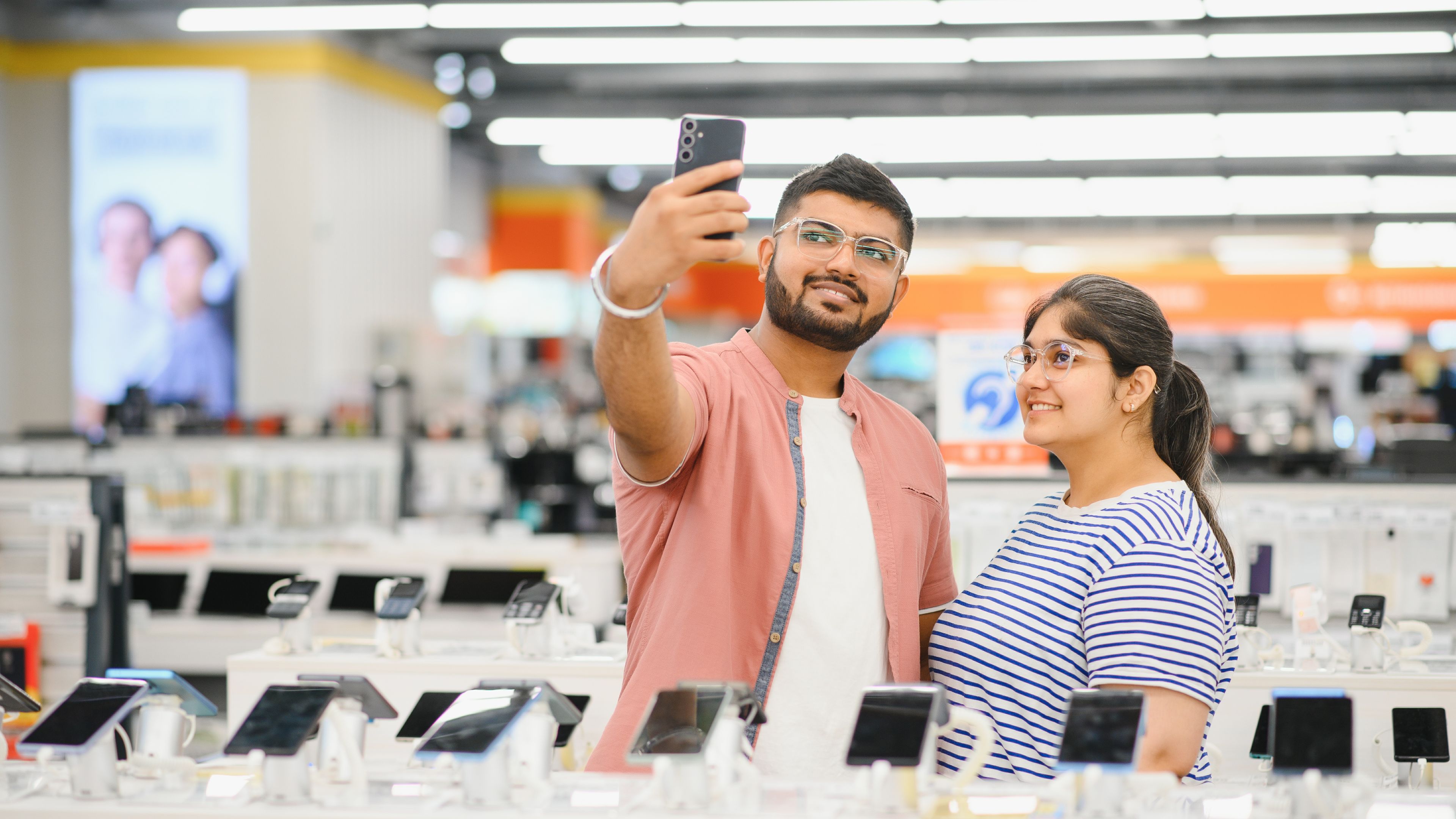 A happy couple taking a selfie in a mobile shop 
