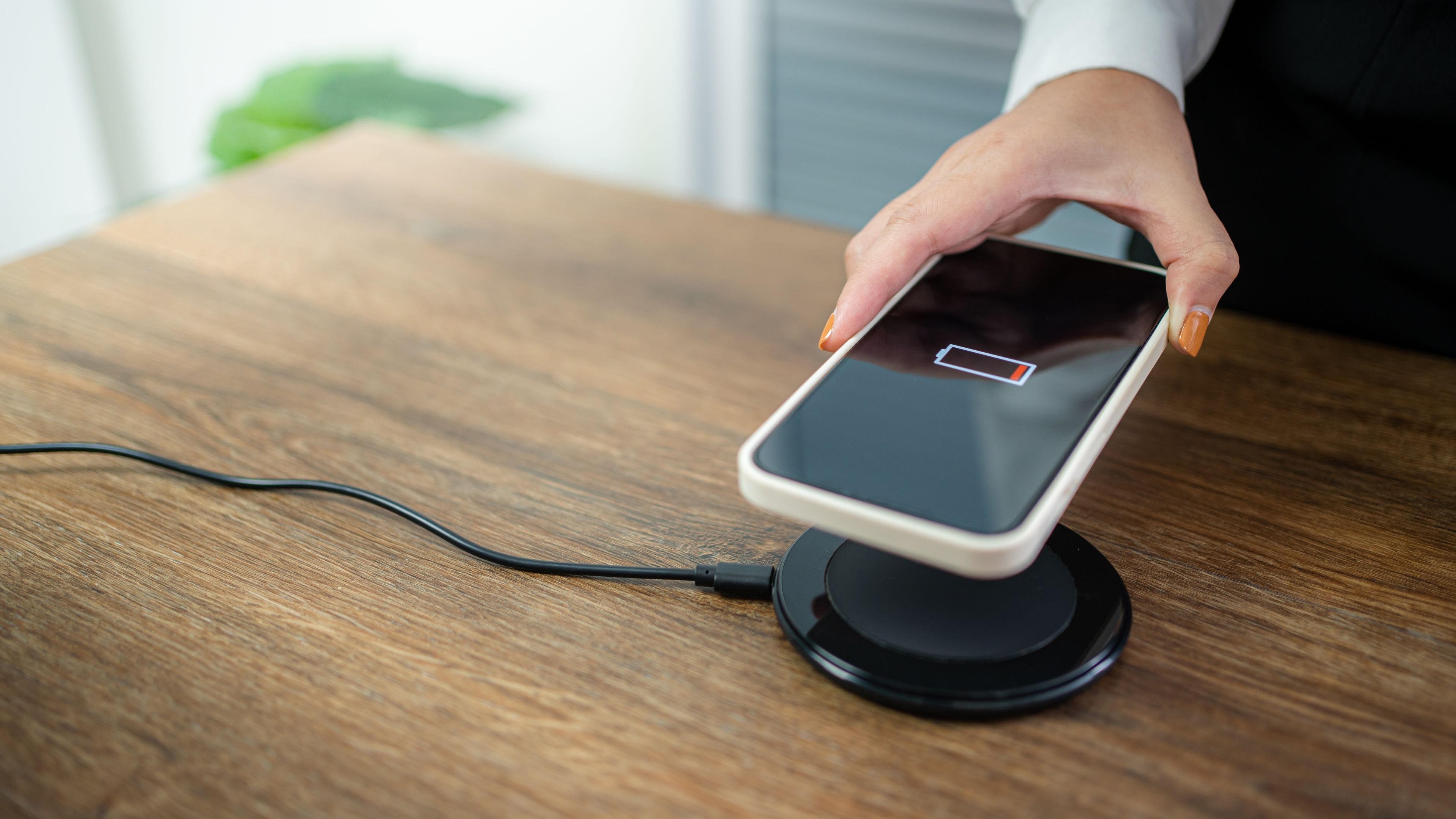 Charging mobile phone battery with wireless charging device in the table