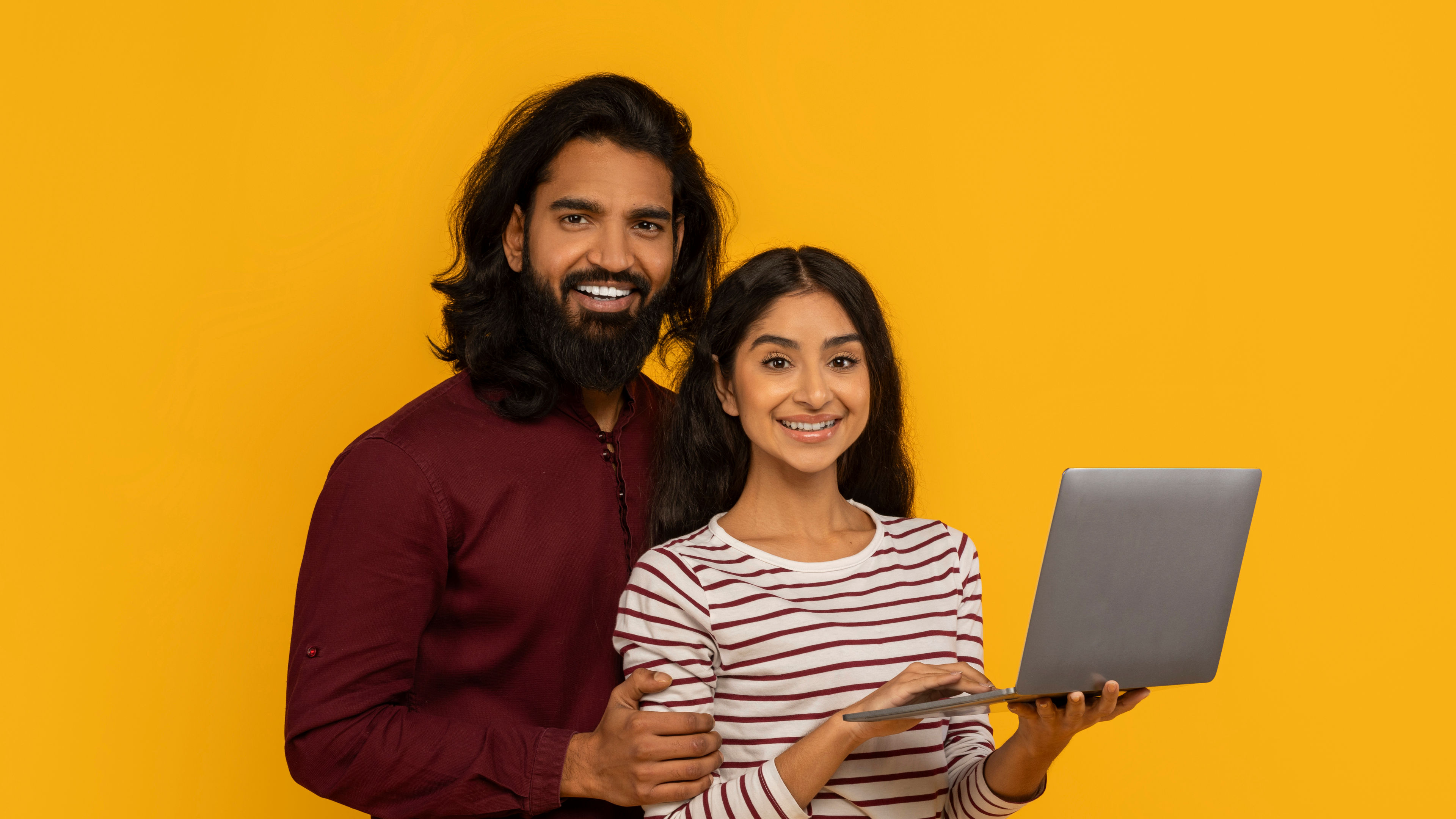 Man and woman holdig a laptop and smiling