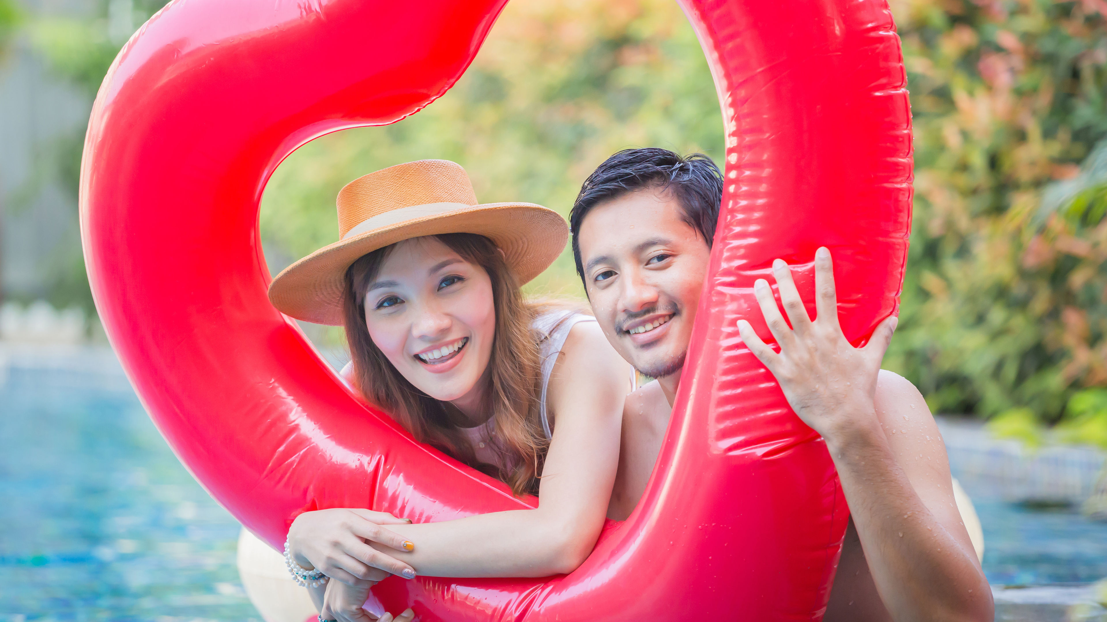 Smiling Couple Relaxing Together by Tropical Pool