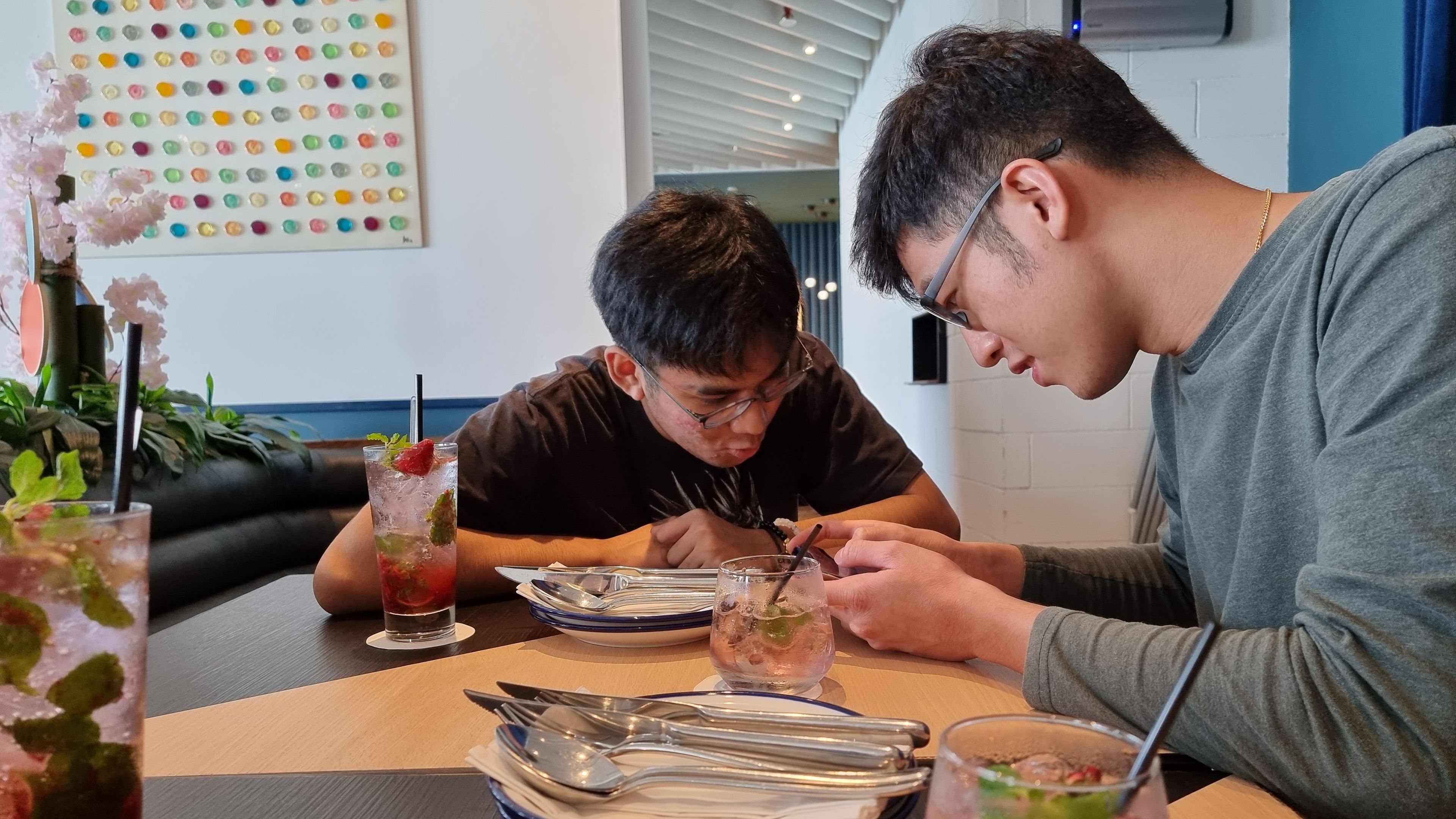 People stay connected by checking social media and enjoying conversations while waiting for their food. 