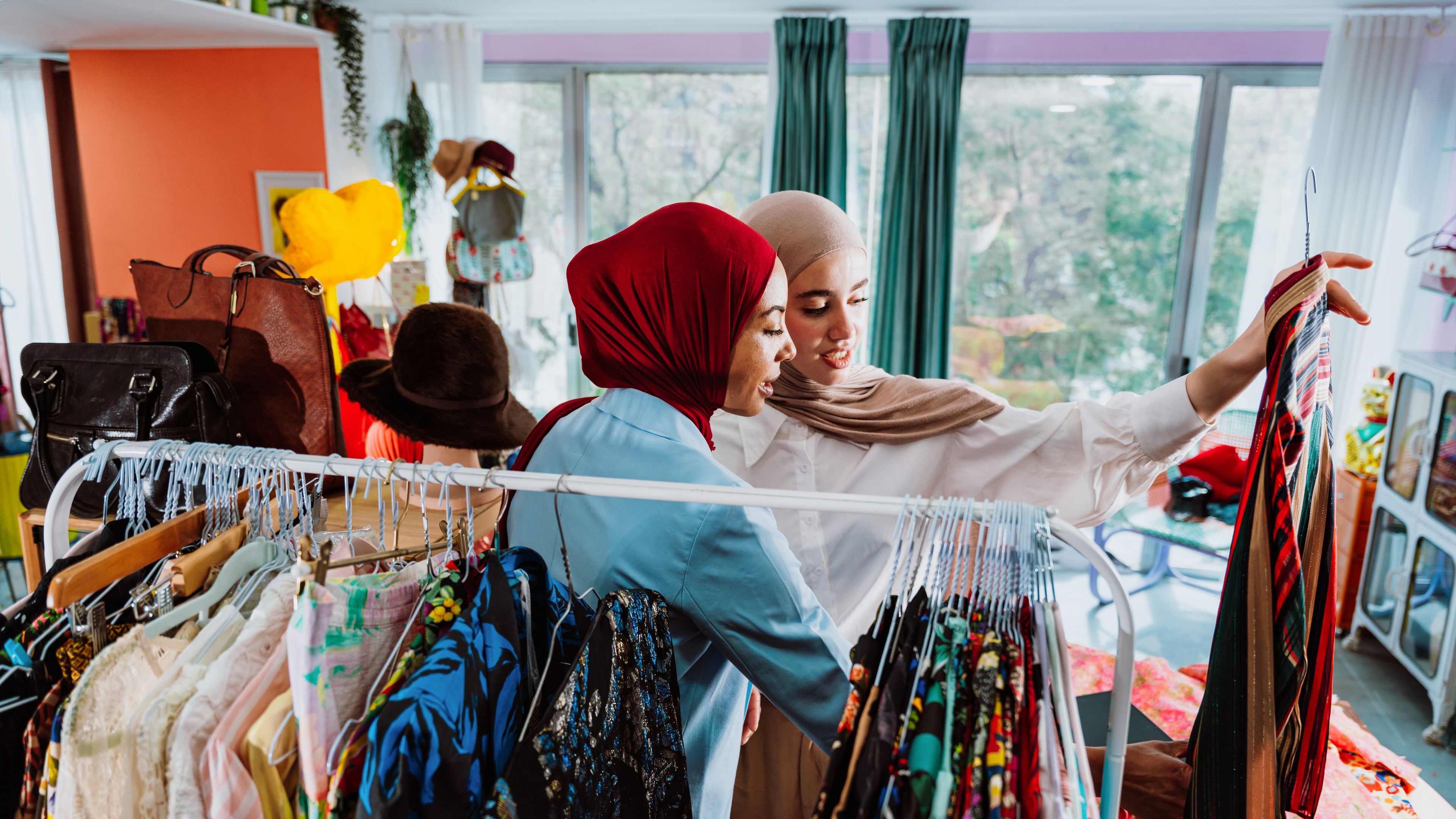 Modern, diverse muslim women shopping for clothing on a digital tablet 