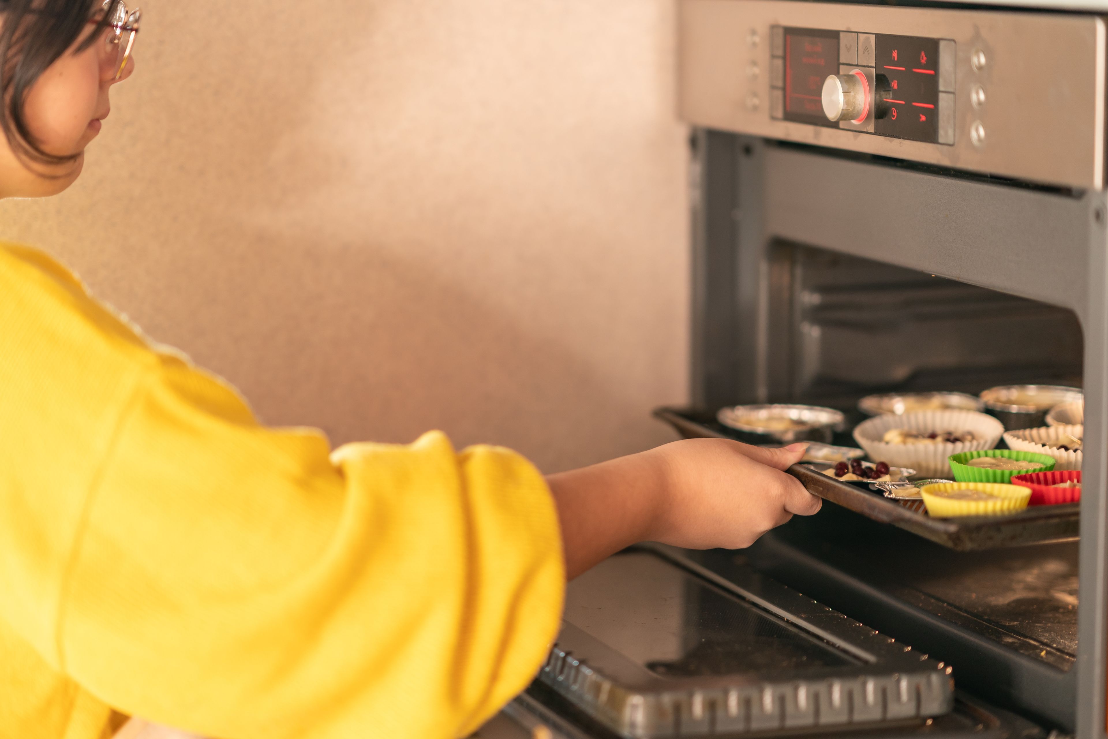 the girl puts a baking sheet of muffins in the oven