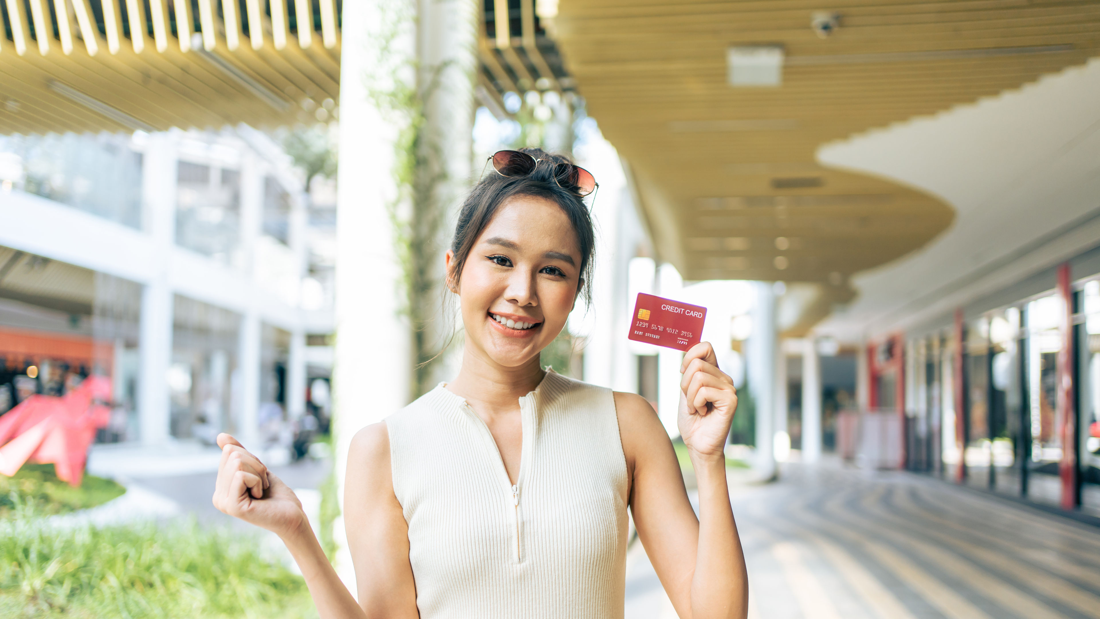 Portrait of Asian attractive girl shopping outdoor in department store. Beautiful woman holding shopping bags then walking alone with happiness, enjoy purchasing in shopping mall and look at camera. 