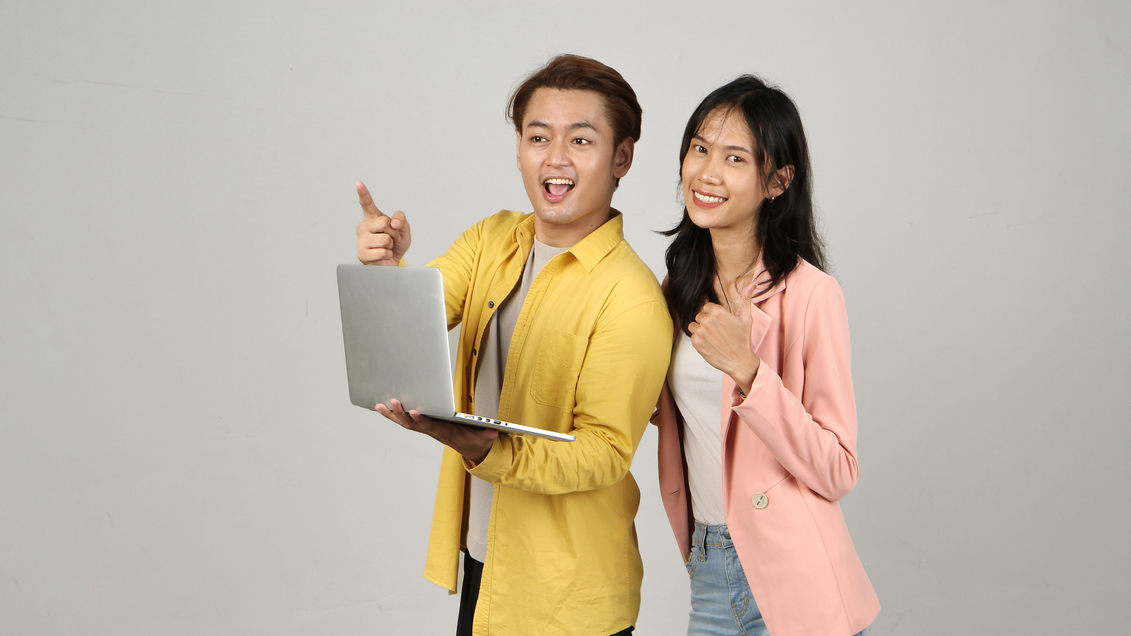 portrait of happy asian couple holding laptop computer and phone  