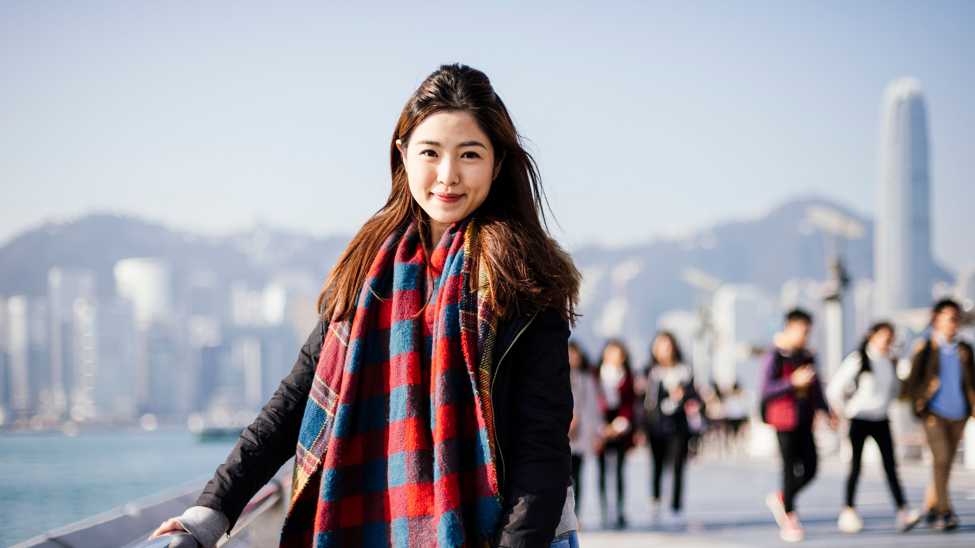 Portrait of young woman wearing checked scarf and leather jacket, looking at camera 
