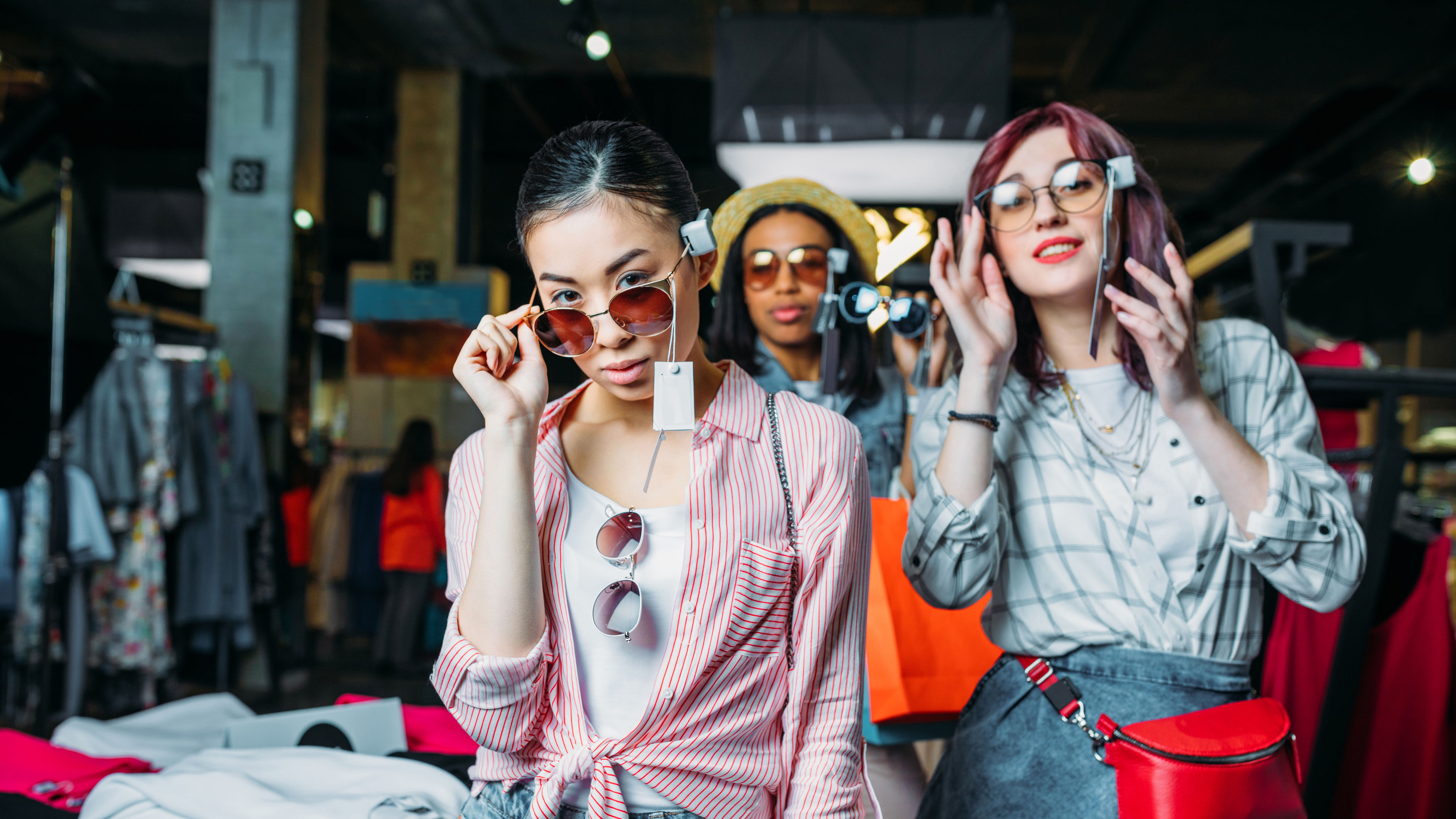 multicultural hipster girls choosing clothes in boutique, fashion shopping girls concept