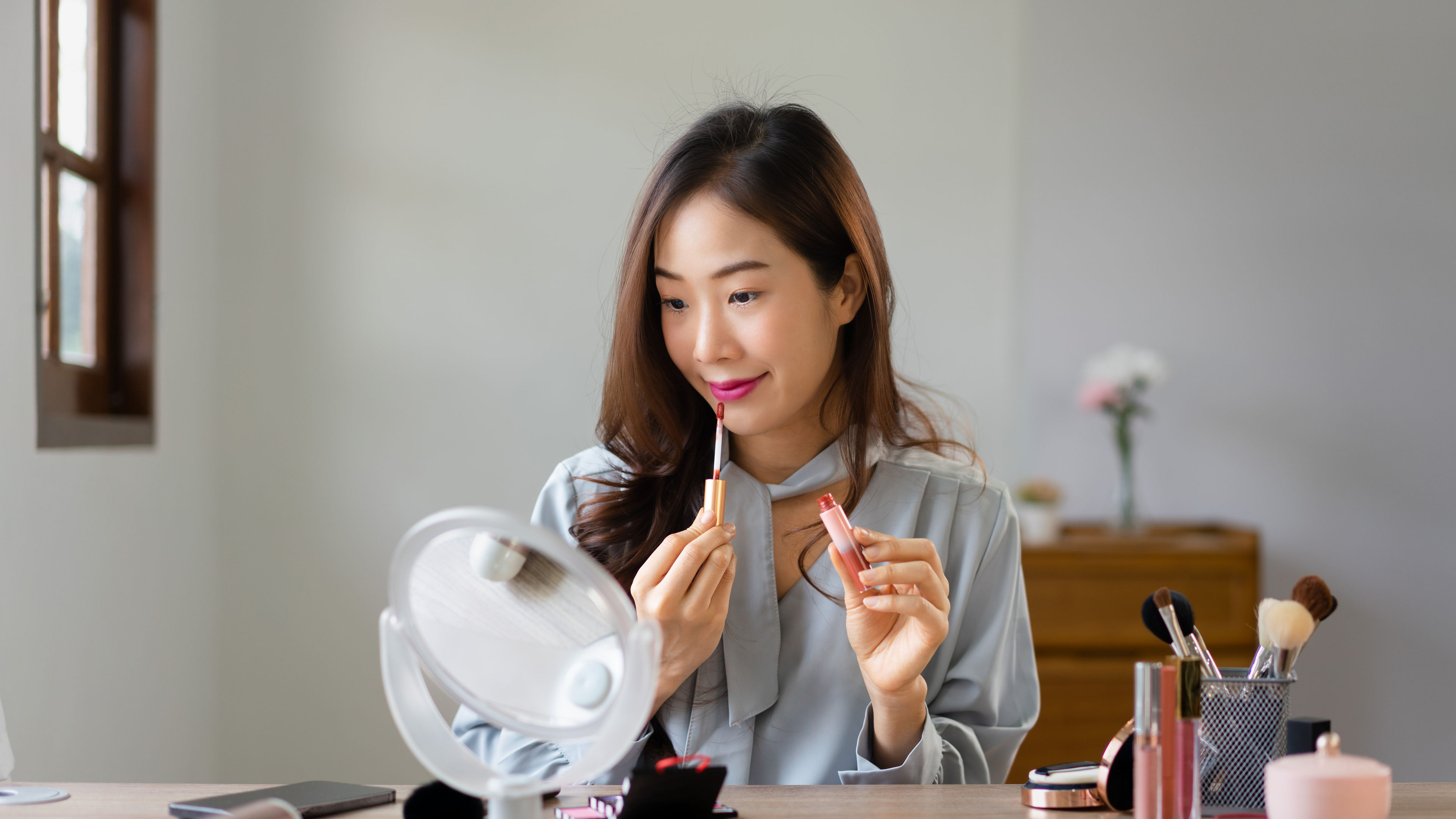 Beauty blogger applying lipstick on her mouth and reviewing cosmetics product in makeup vlogger.