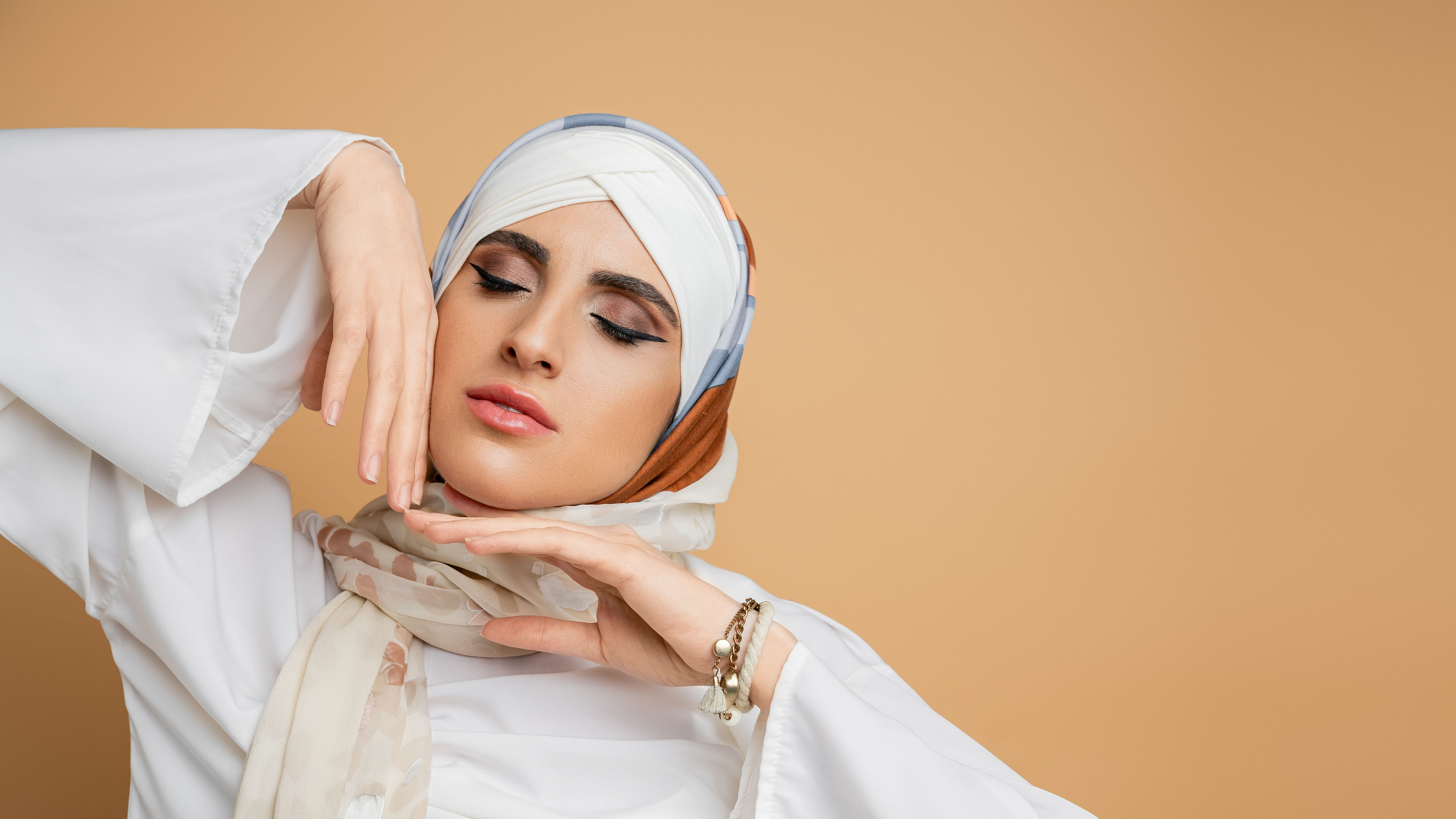 Portrait of a sensual muslim woman in silk scarf posing with closed eyes