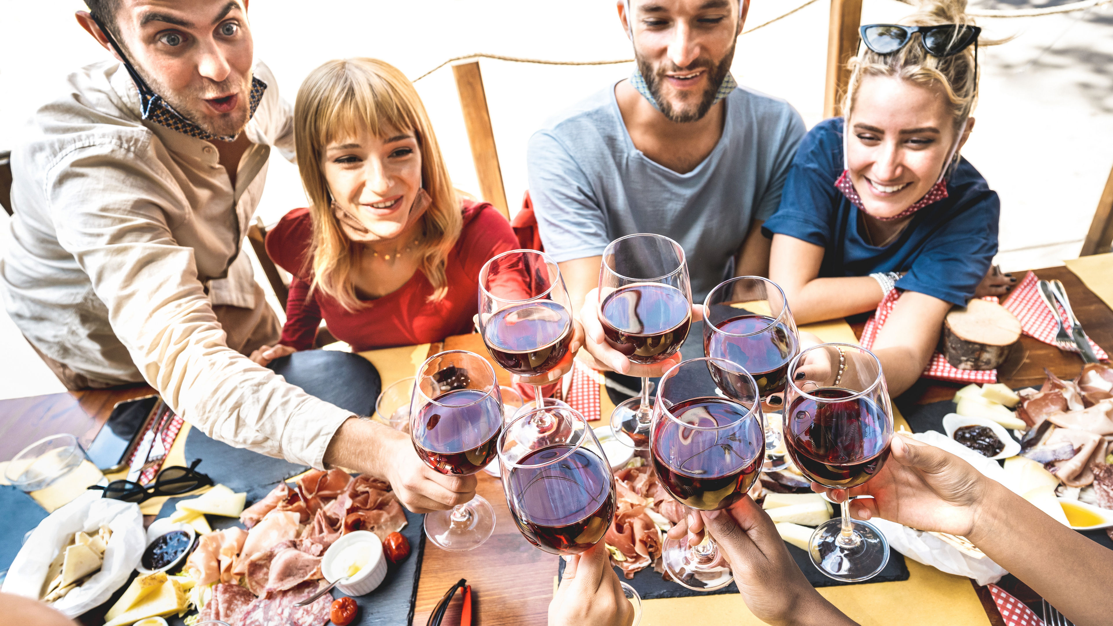A group of friends raising their glasses of red wine for a toast 