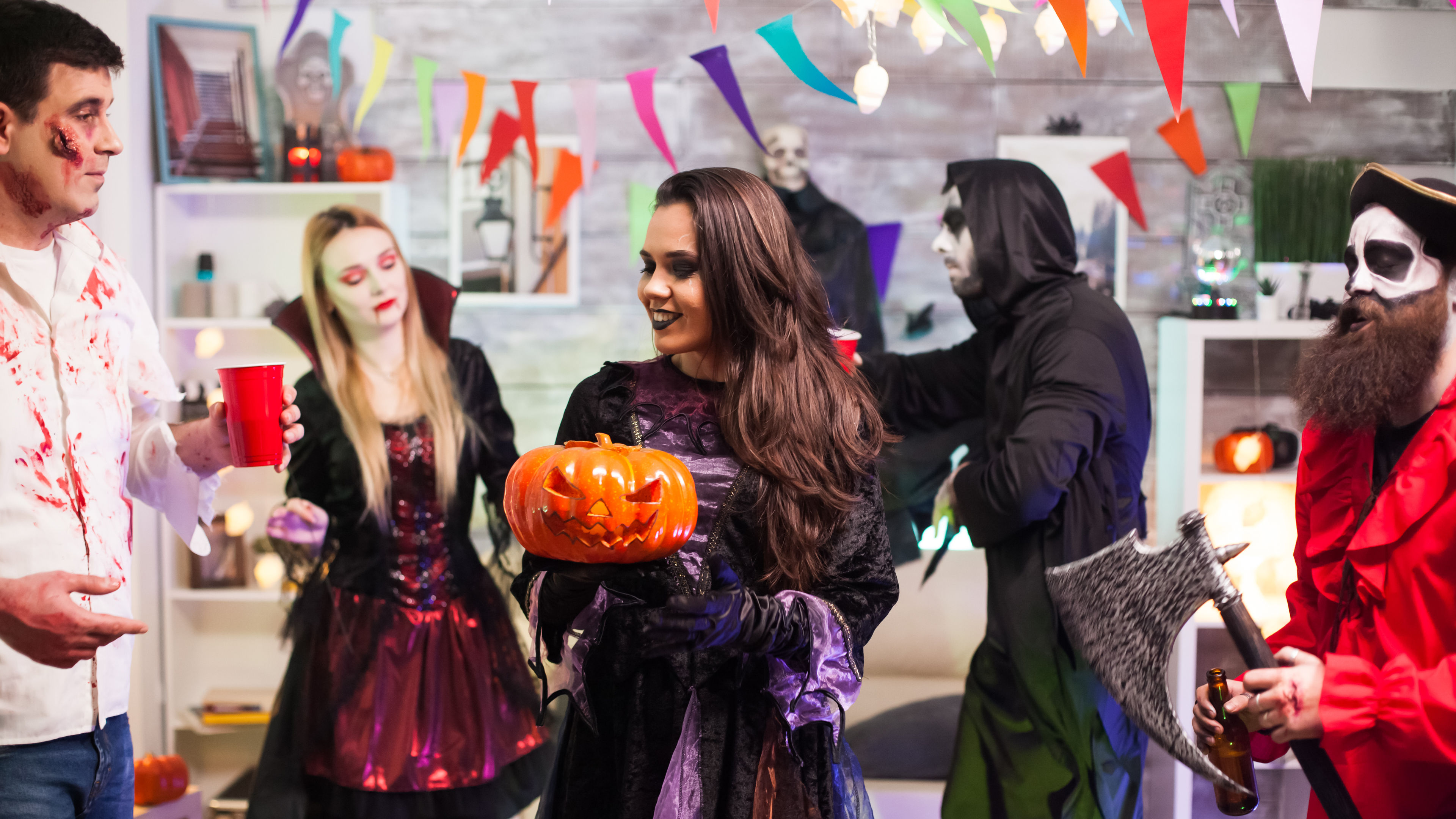 A cheerful woman dressed in a vibrant witch costume, exuding confidence and charm, captures the essence of festive spirit