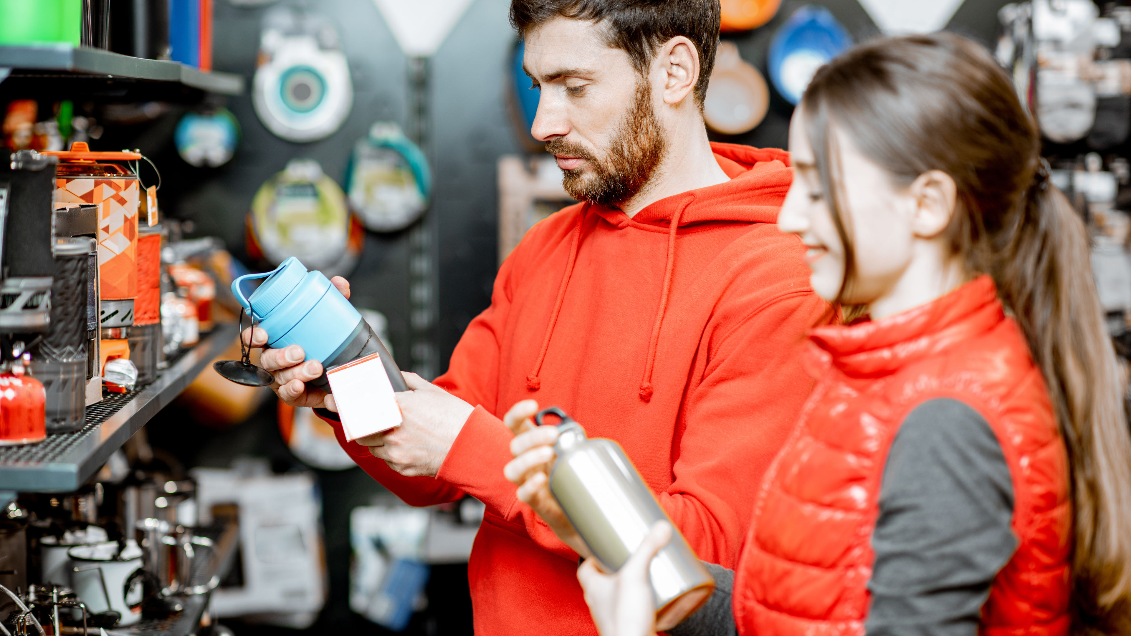 Couple choosing camping dishes in the shop 
