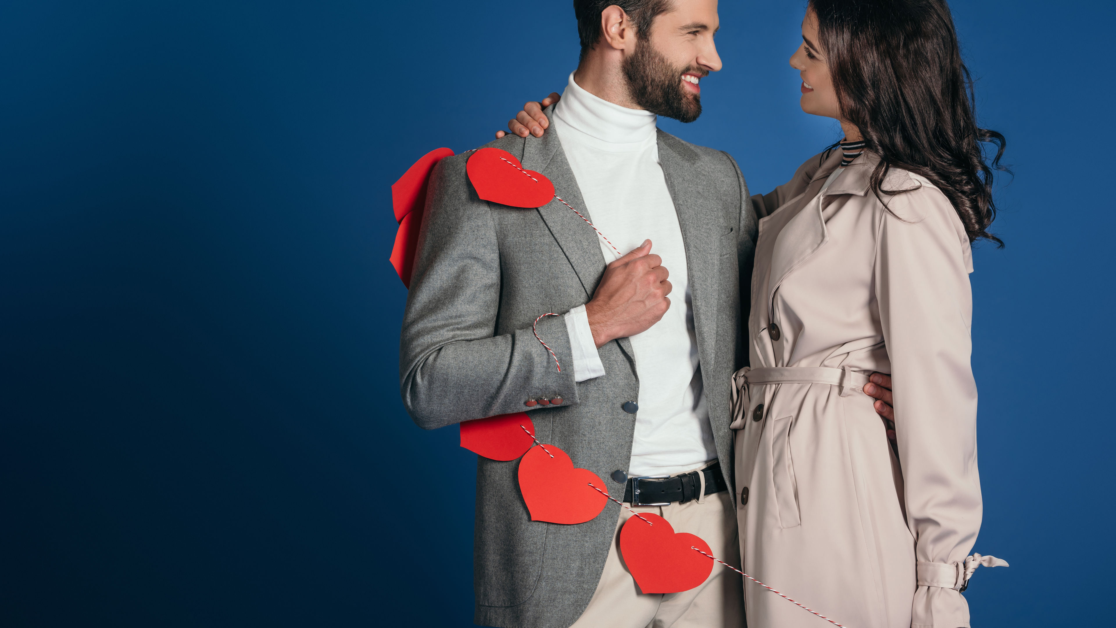 Happy couple holding a garland of red hearts. 
