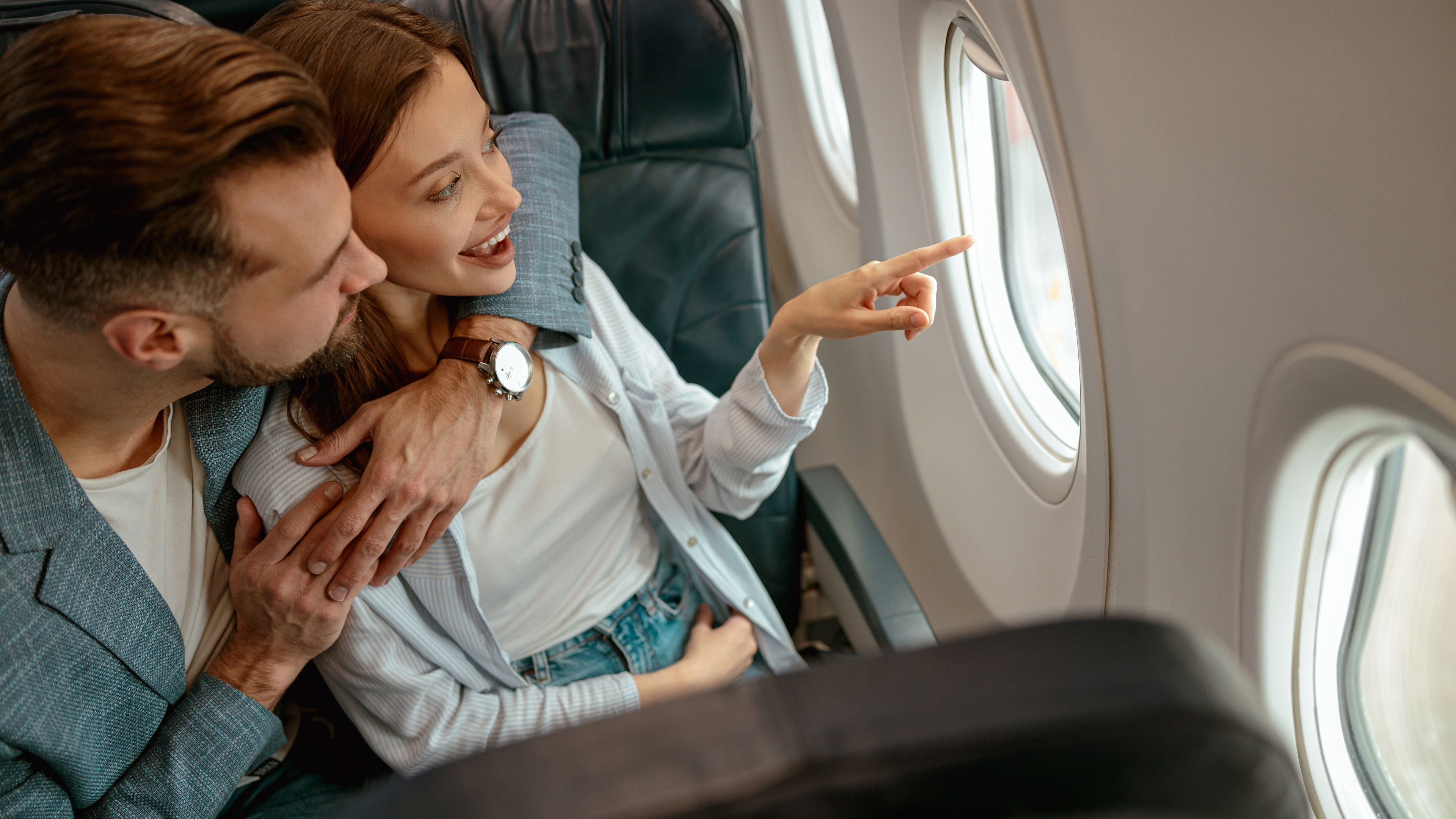 Happy couple in love looking out the window in plane