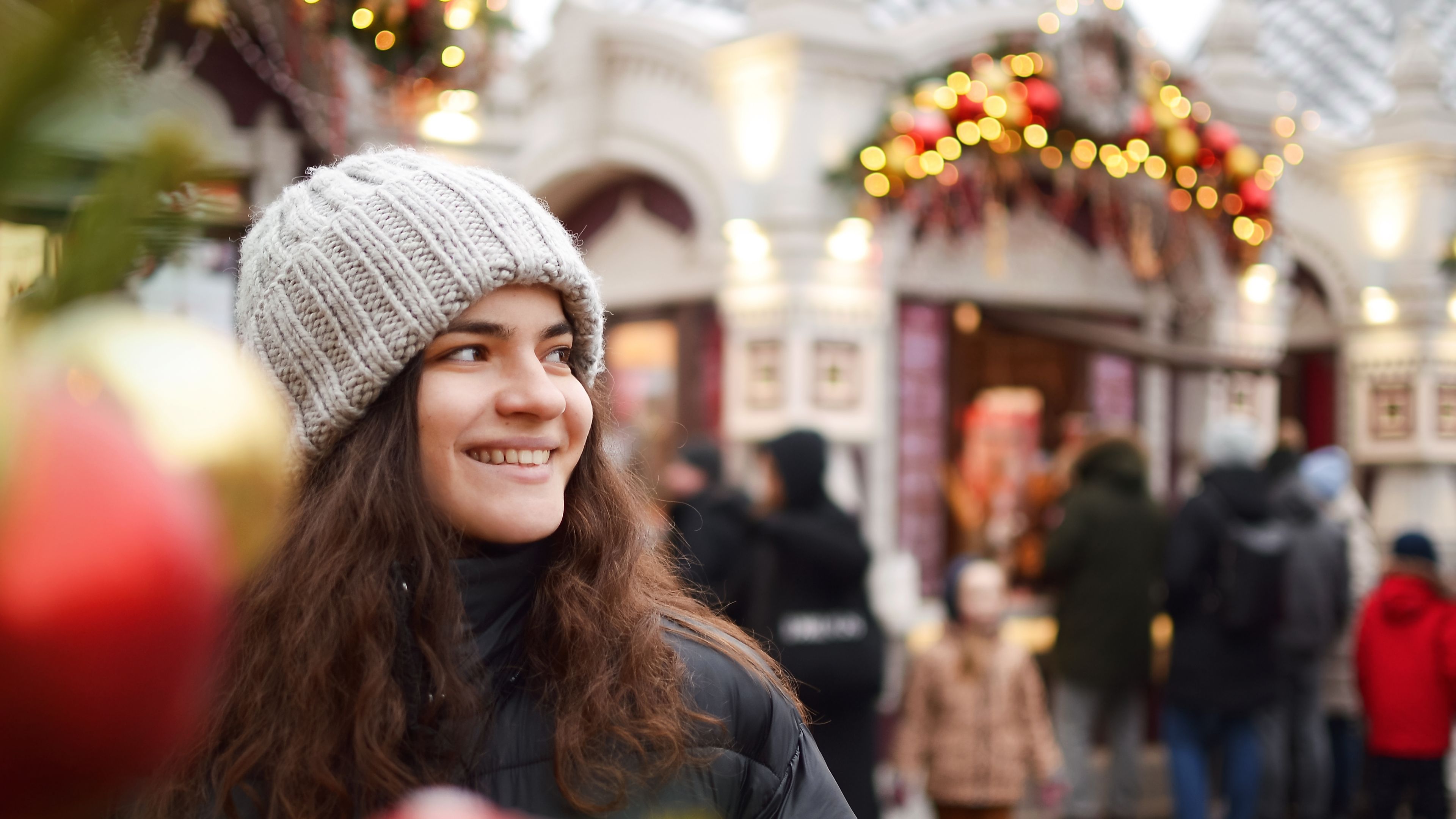 A young, happy woman enjoying the festive atmosphere at a Christmas market. 
