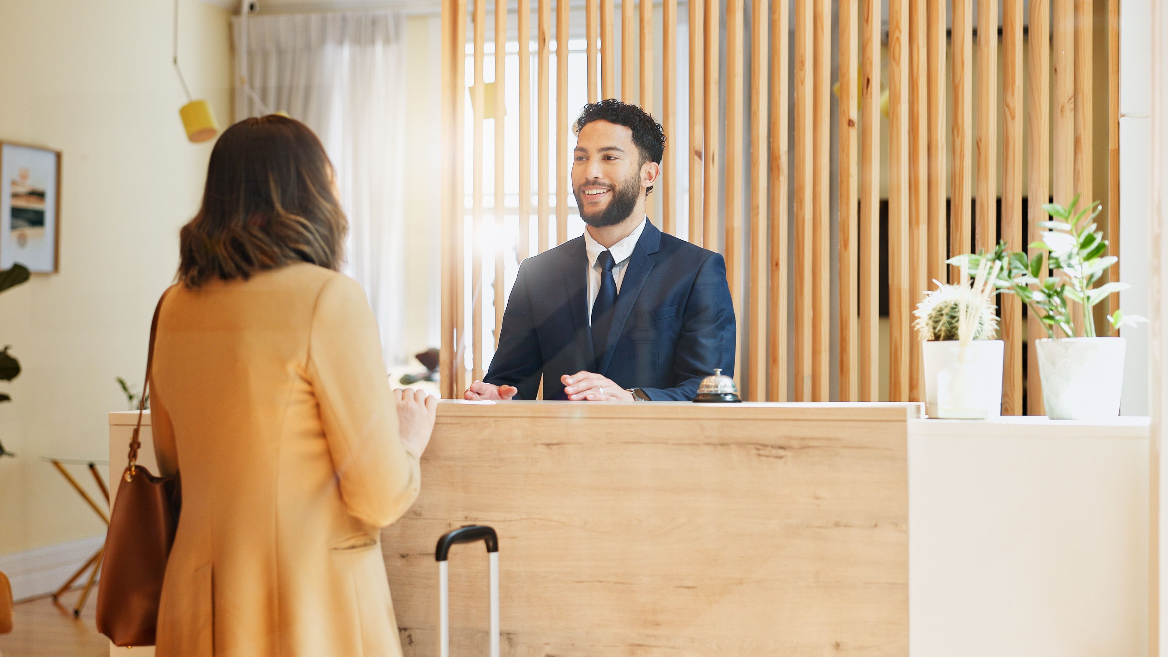 Hotel, check in and woman at desk with man, smile and friendly reception service for hospitality