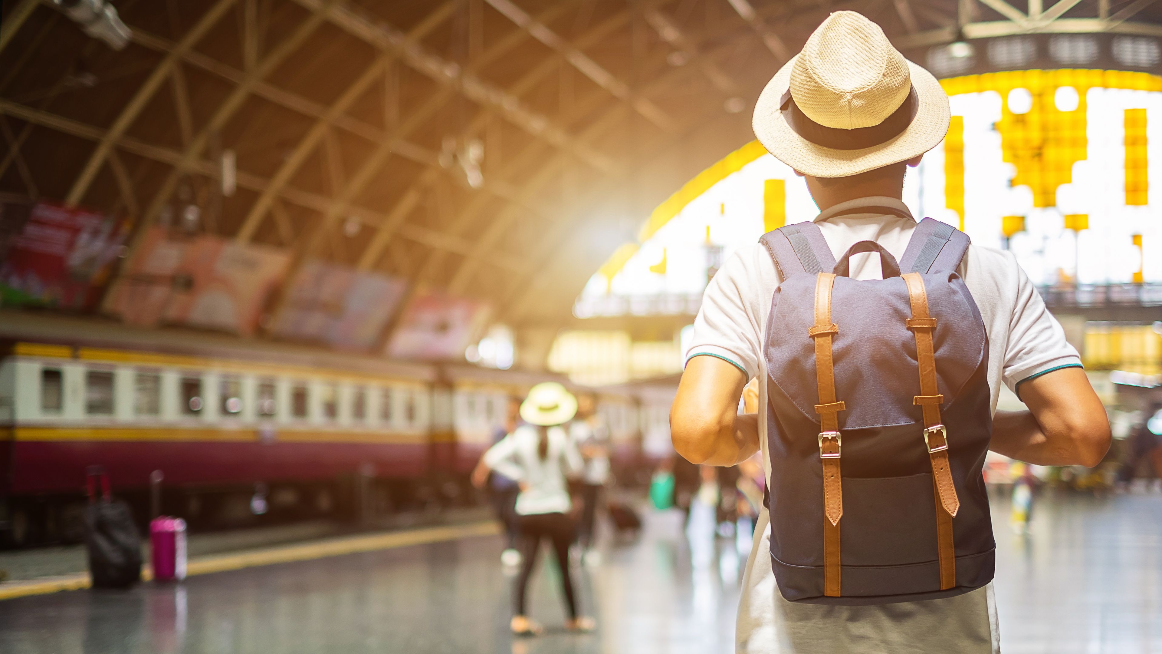 man traveler with backpack waiting for train, backpacker standing on railway platform at Bangkok