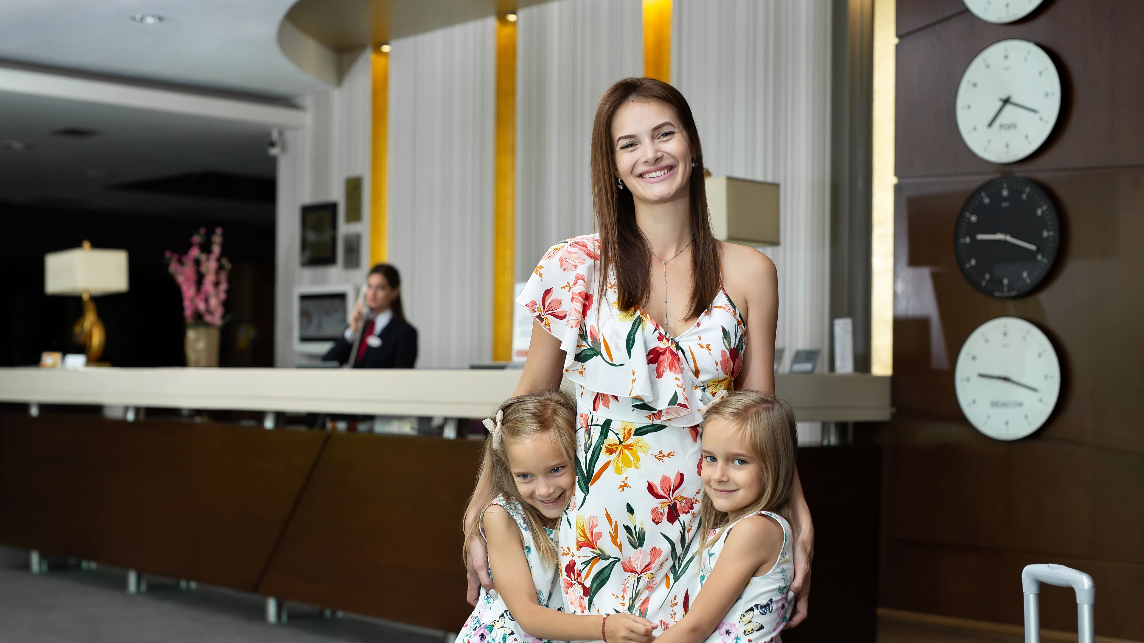 Mother with twin daughters hugging at the hotel reception