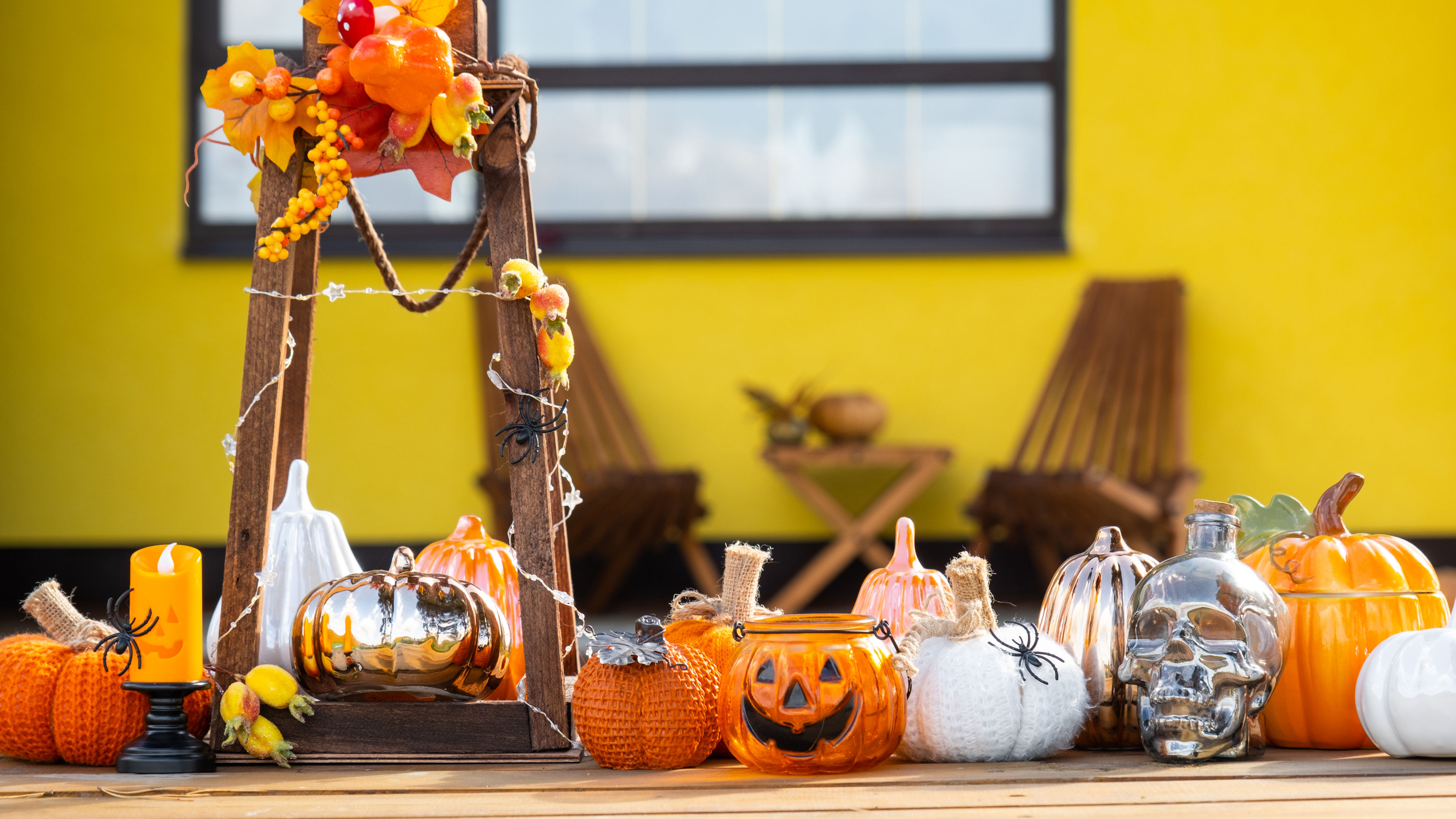 A colorful autumn-themed porch decorated with pumpkins, candles, and fall leaves 