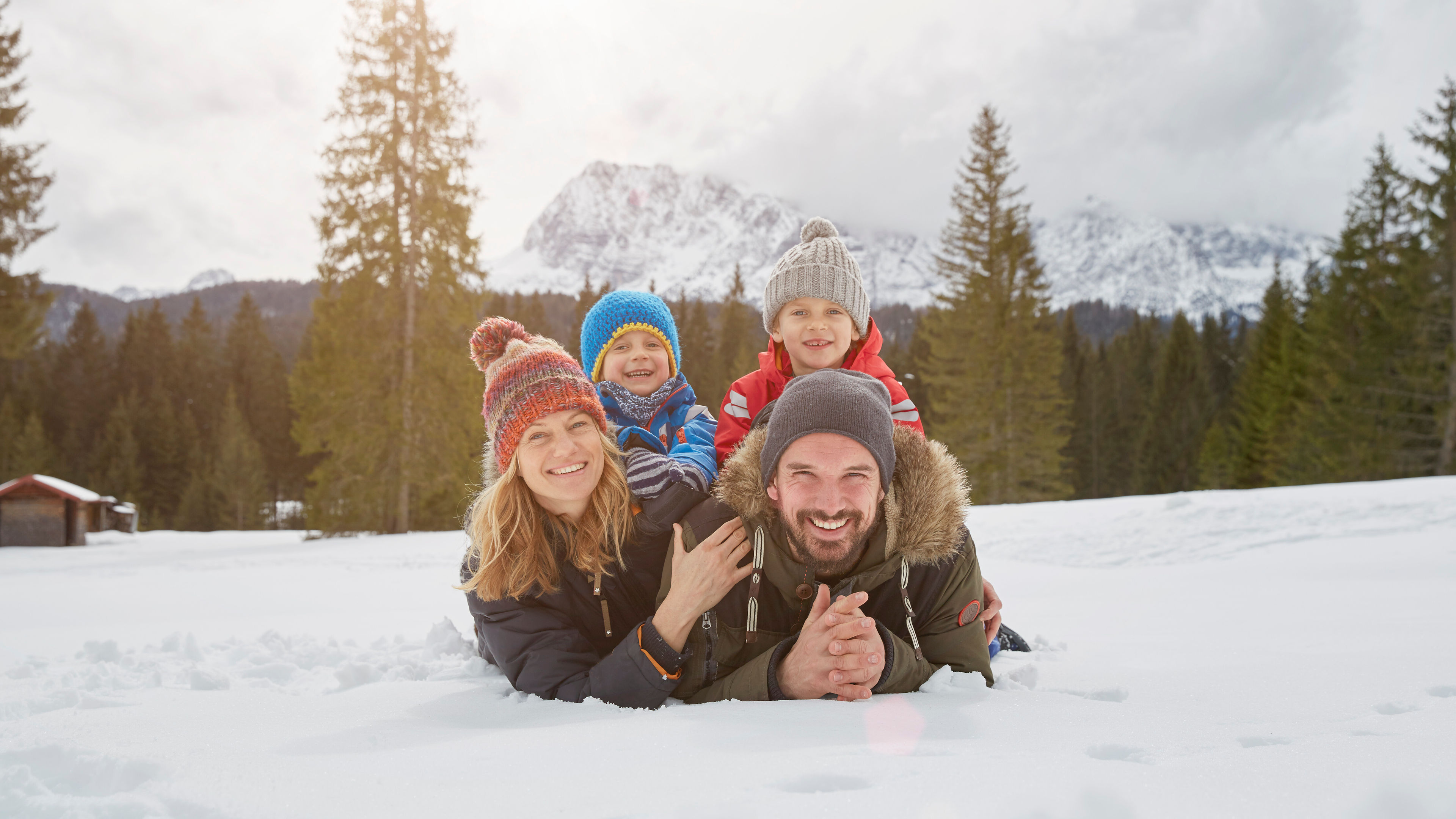 Portrait of parents and sons lying in snow covered landscape 