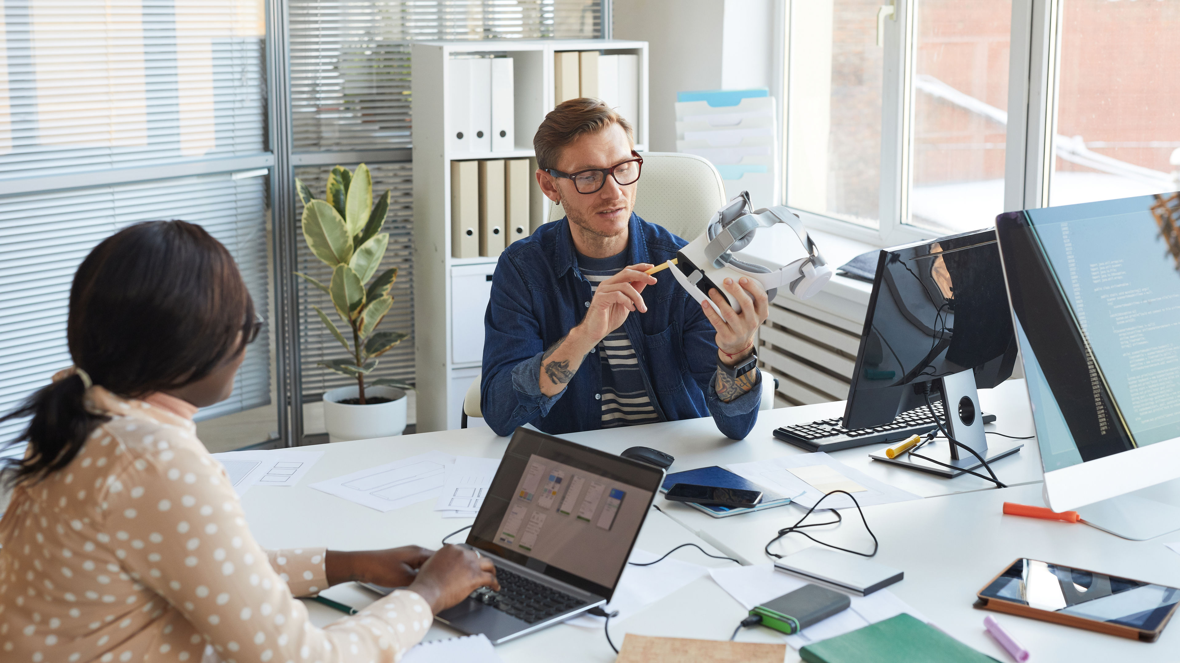 Portrait of modern IT developer holding VR headset and while working on augmenter reality games and software 