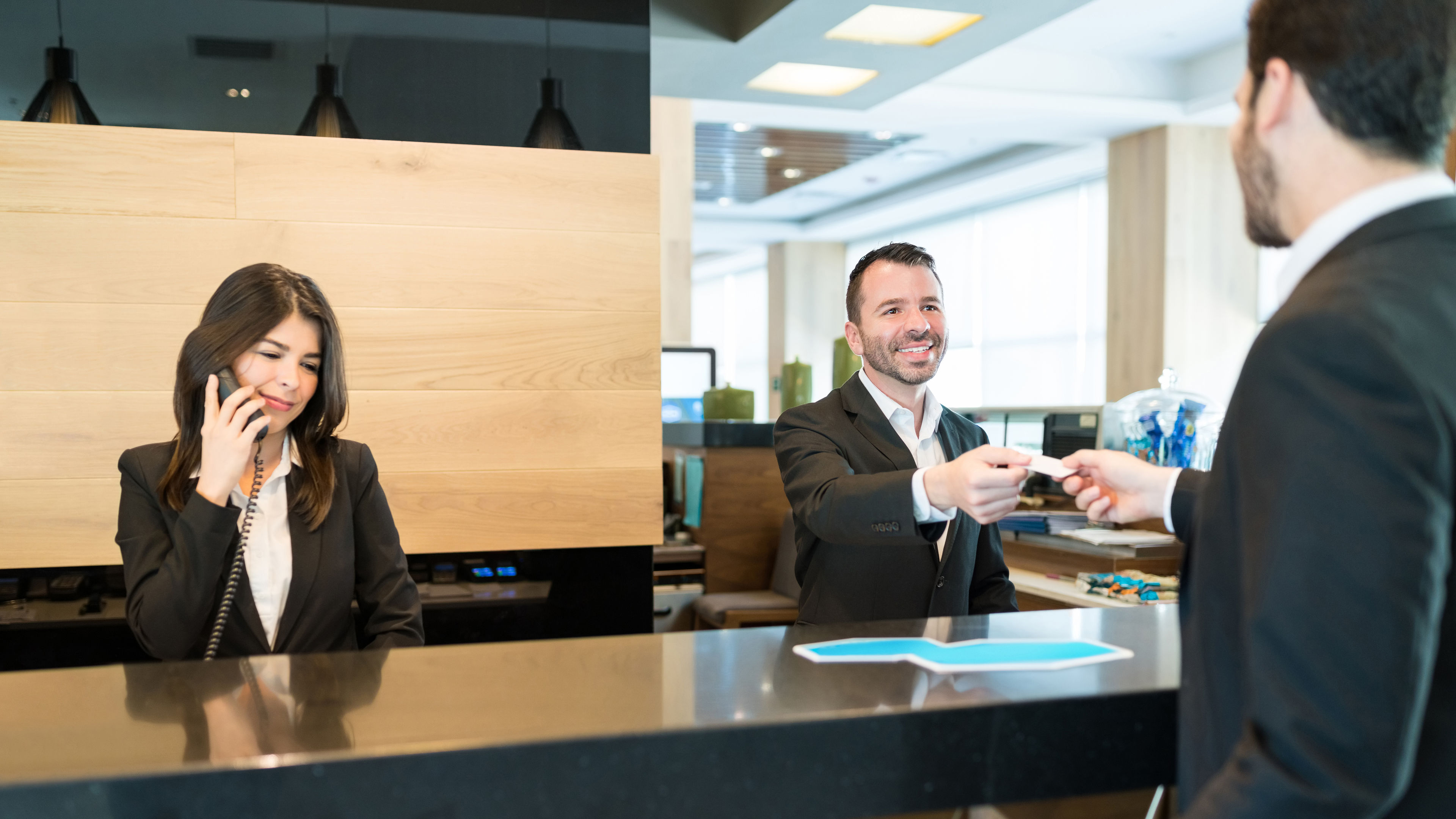 Receptionist Giving Card Key To Businessman At Lobby