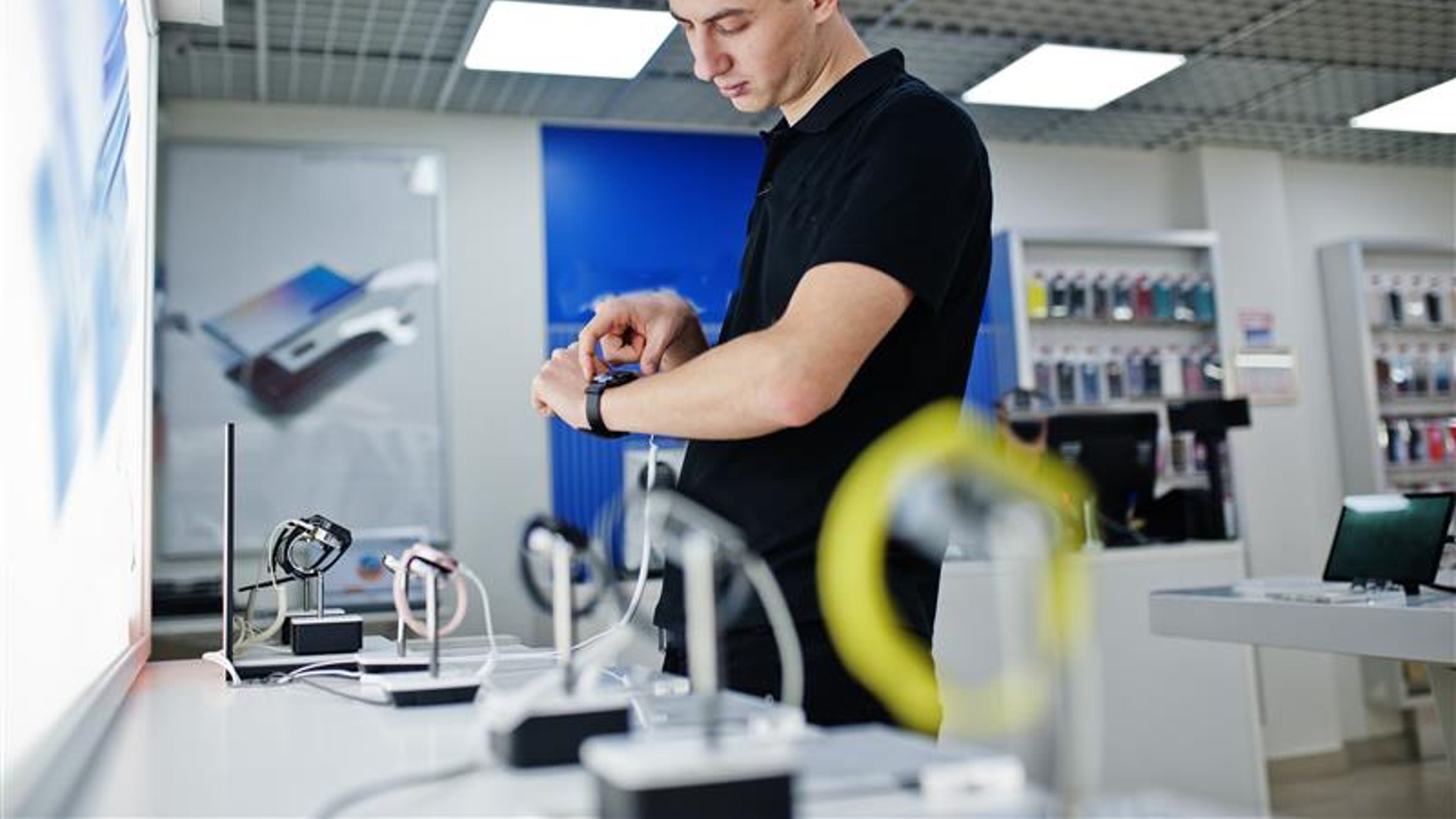 Seller man mobile phone professional consultant in tech store or shop check new smart watches. 