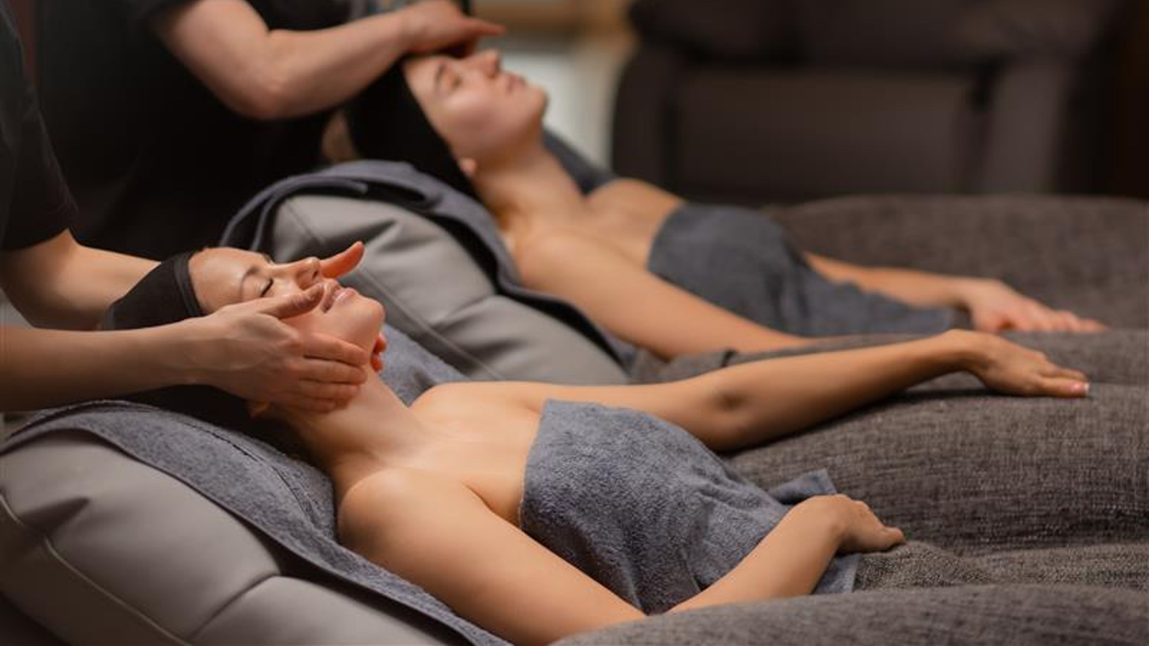 Two attractive women are pampered themselves at the health spa, get face lift massage 
