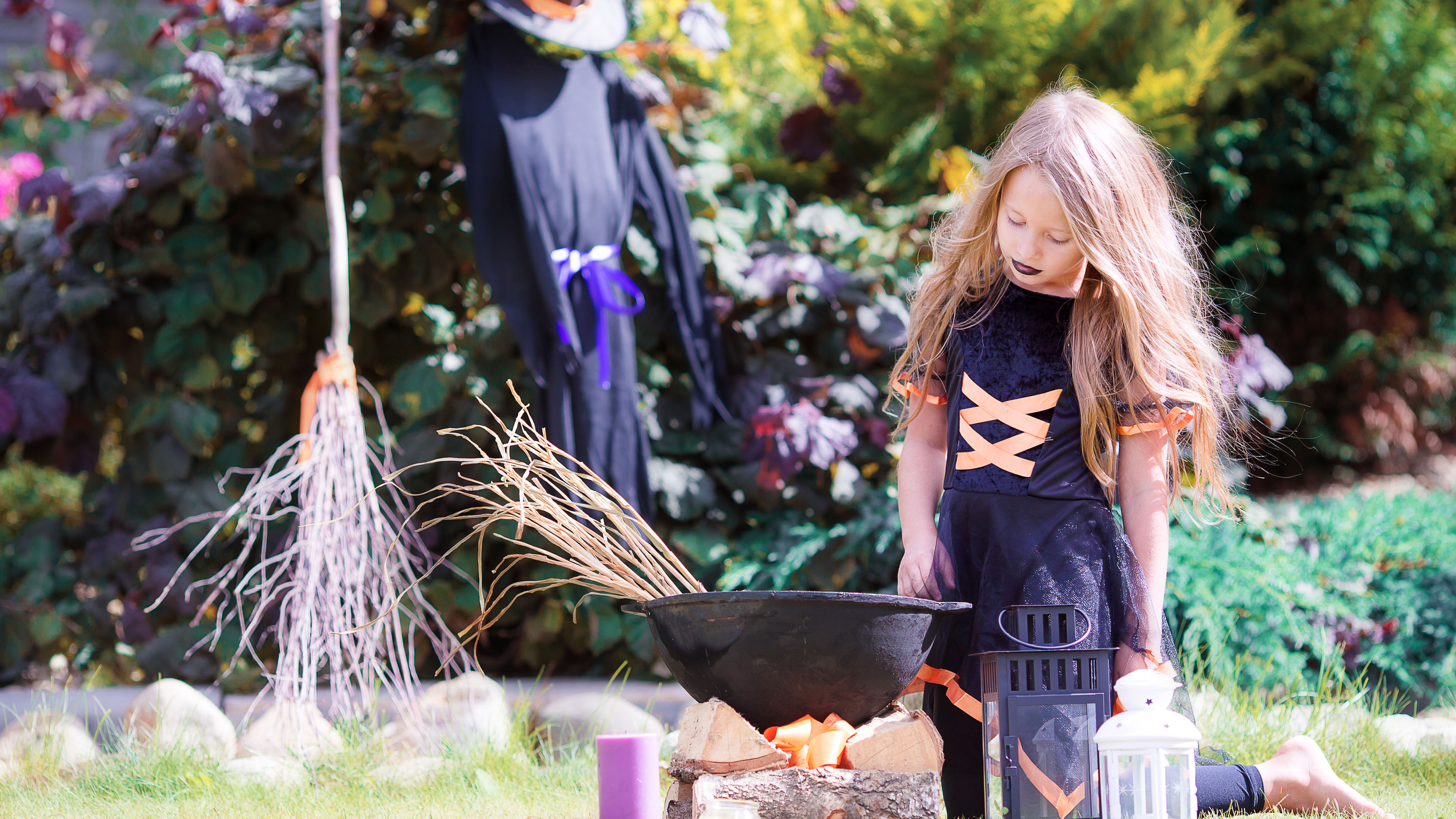 Happy little witch trick-or-treating outdoors on Halloween. 