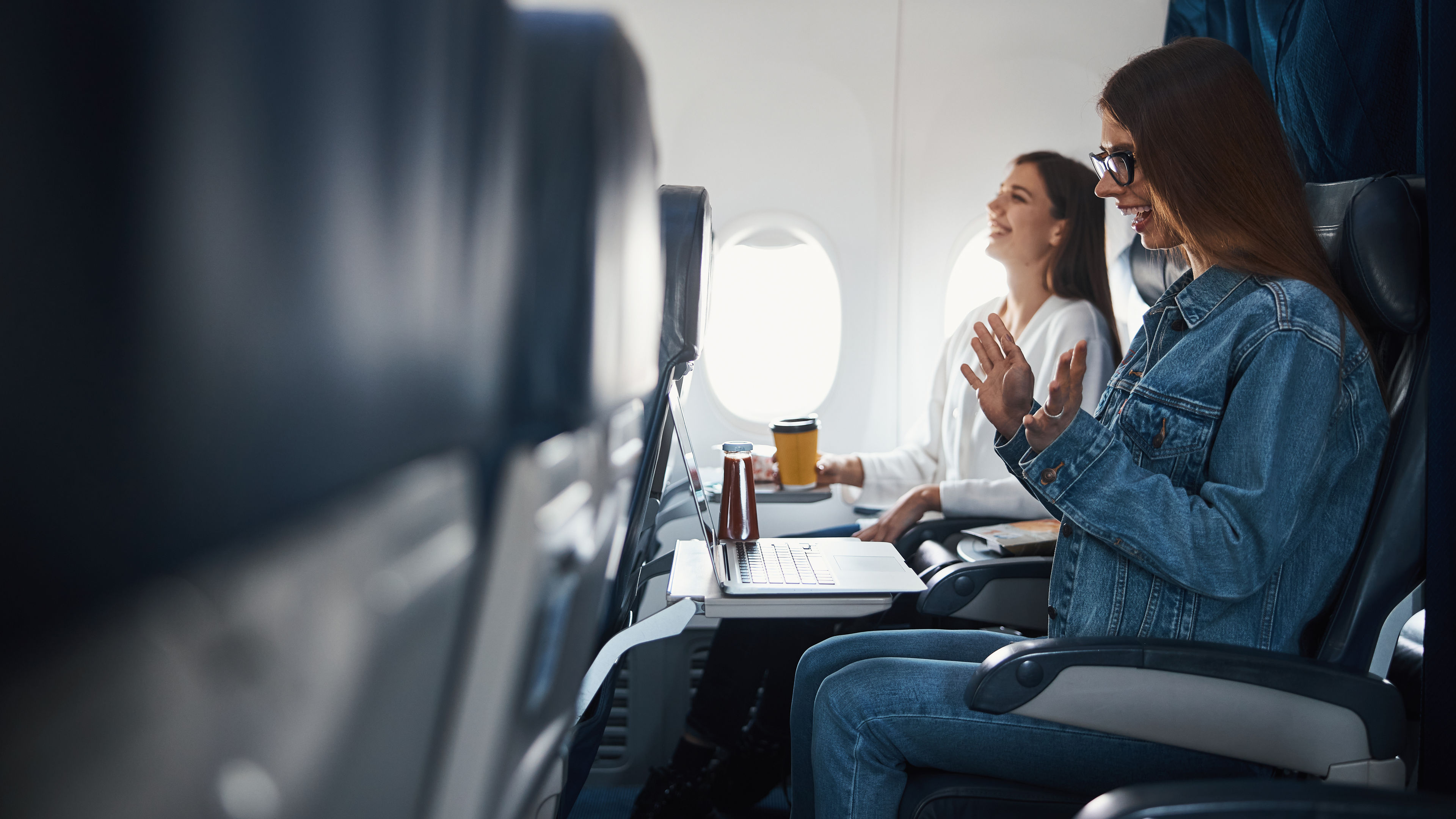 Woman cheering at information received on her laptop during flight 