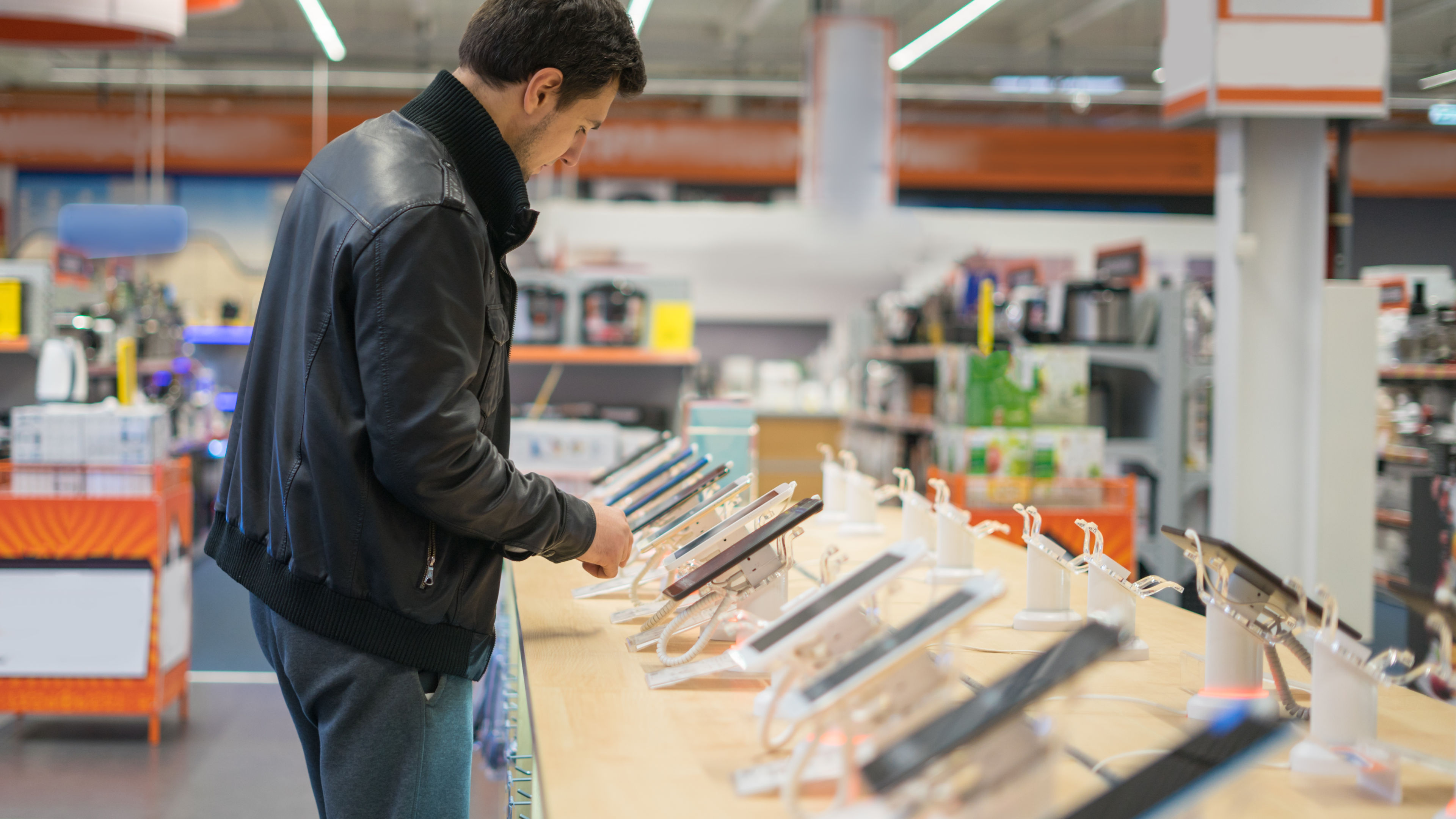 young male customer choosing smartphone in the mobile phone shop 